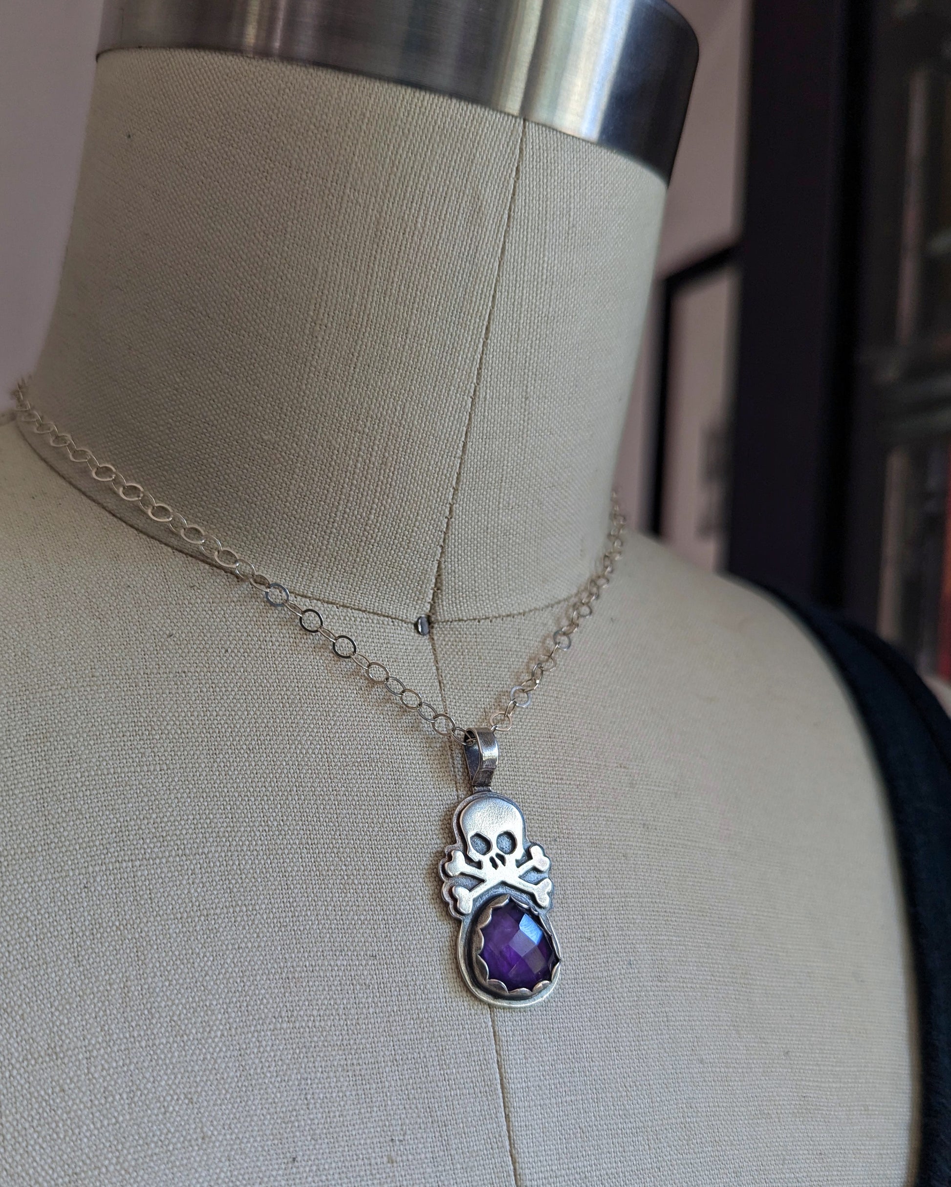Sterling silver skull necklace with a beautiful purple rosecut amethyst shown on a dress form perfect for any Tiki outfit