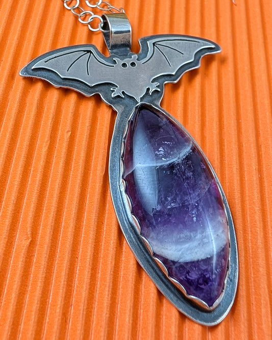 Sterling silver bat necklace with chevron amethyst on orange background