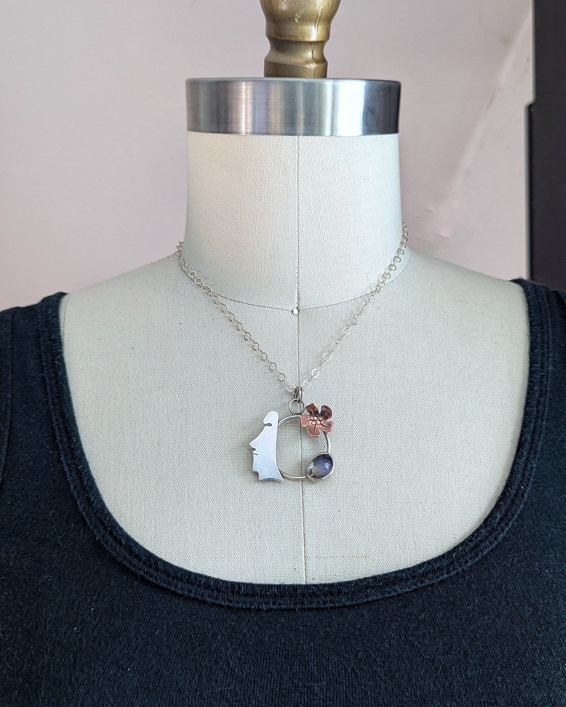 Easter Island Moai statue sterling silver and copper necklace with purple and yellow stone shown on a dress form