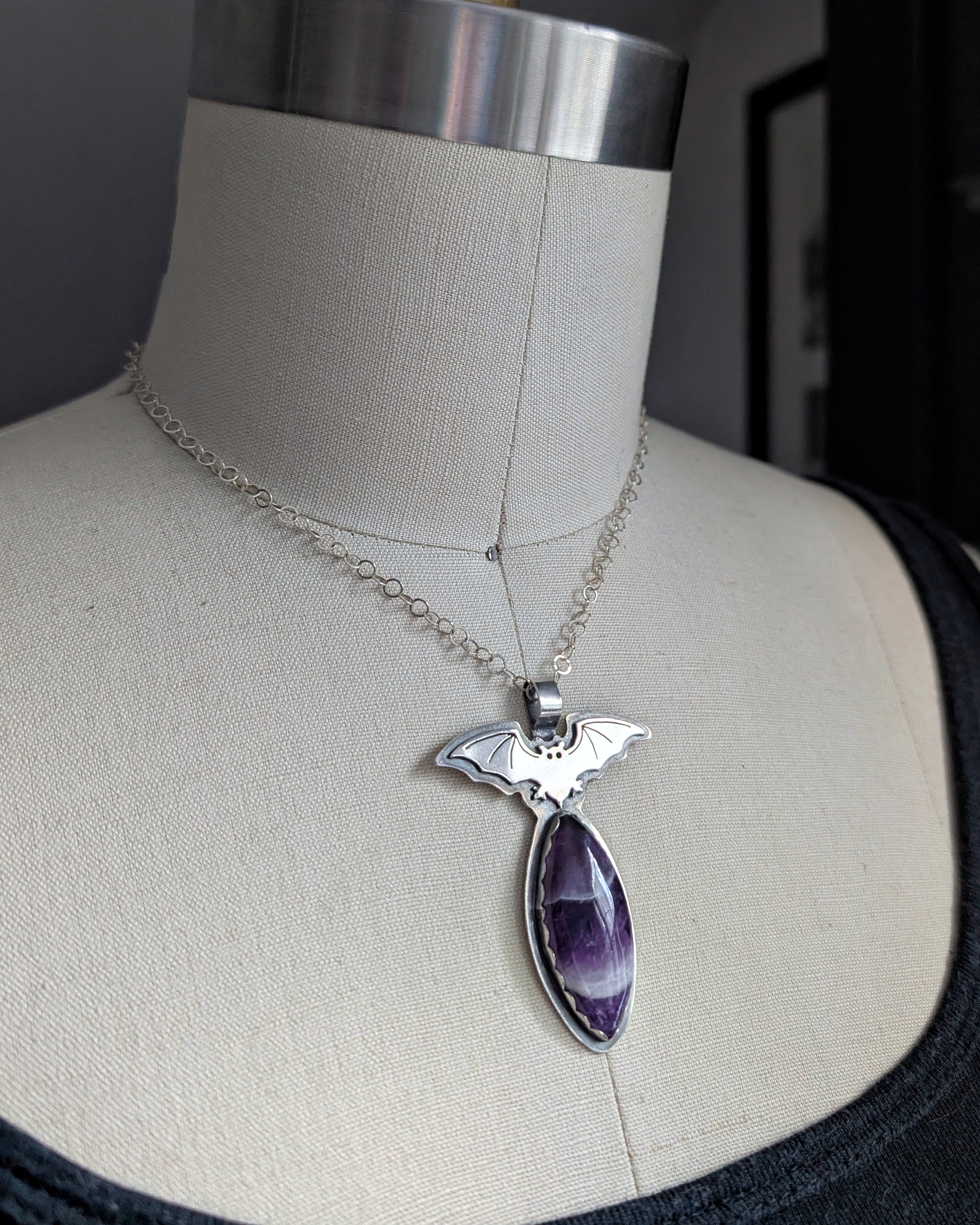 Side view of sterling silver bat necklace with chevron amethyst on a mannequin