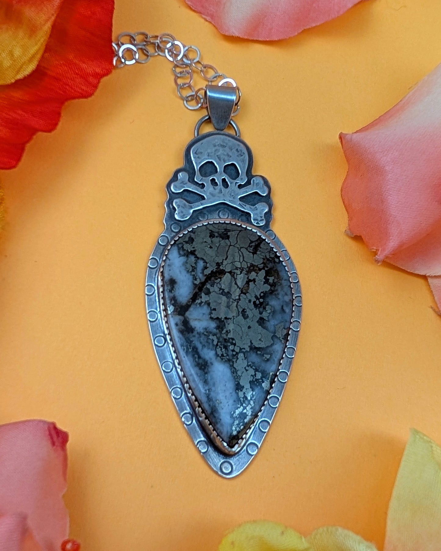 Sterling silver skull necklace with marcasite on a yellow background