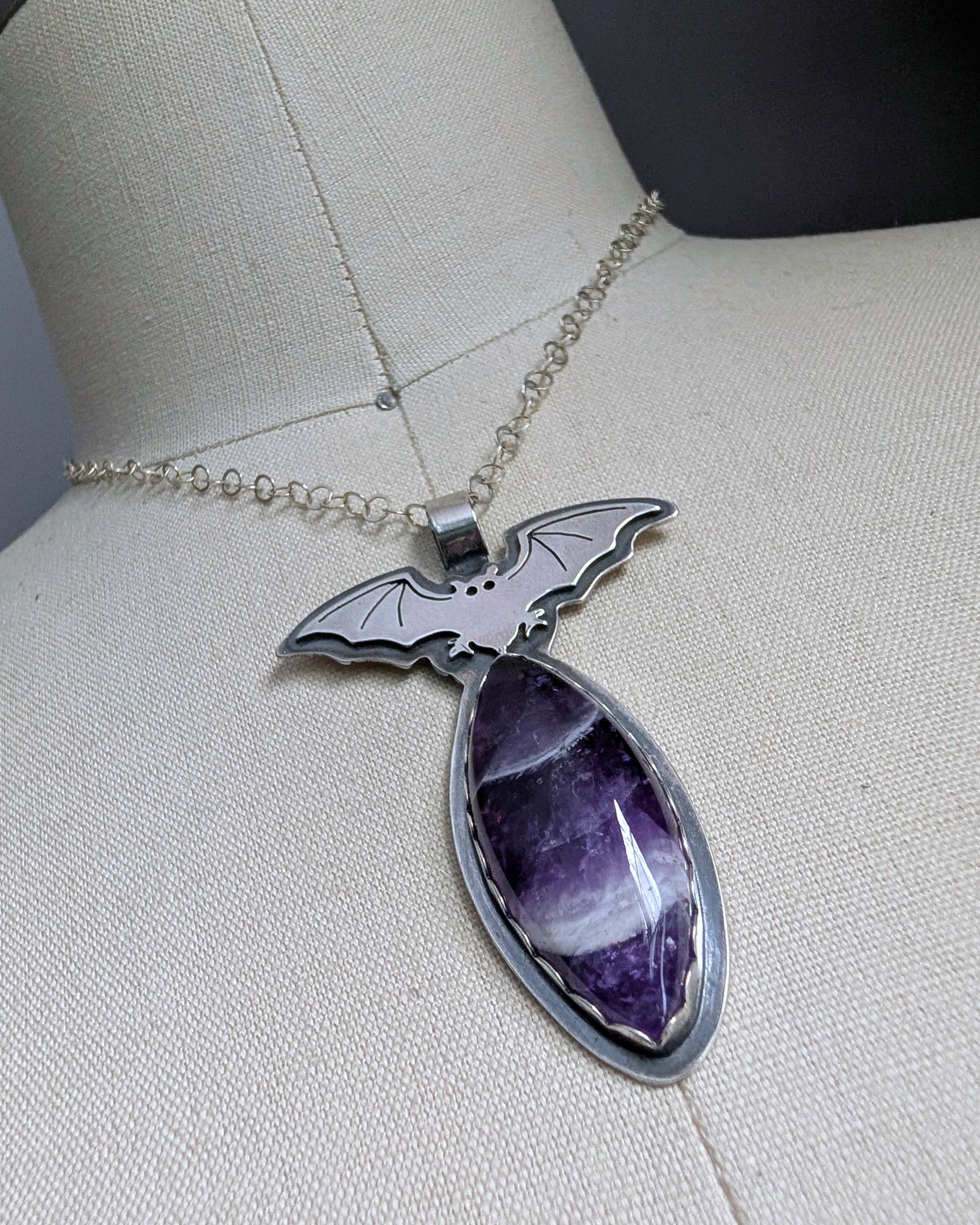 Clos up of sterling silver bat necklace with chevron amethyst on a mannequin