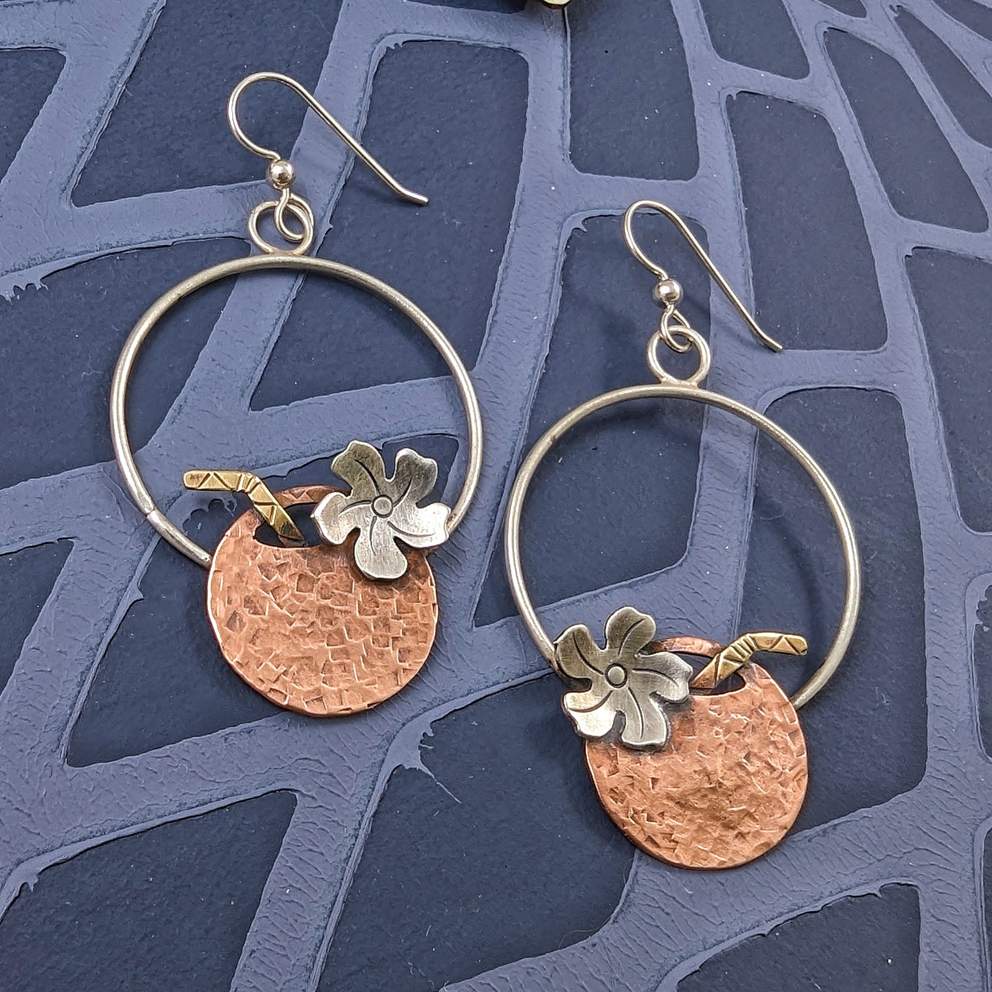 Hammered copper coconut earrings on navy colored background