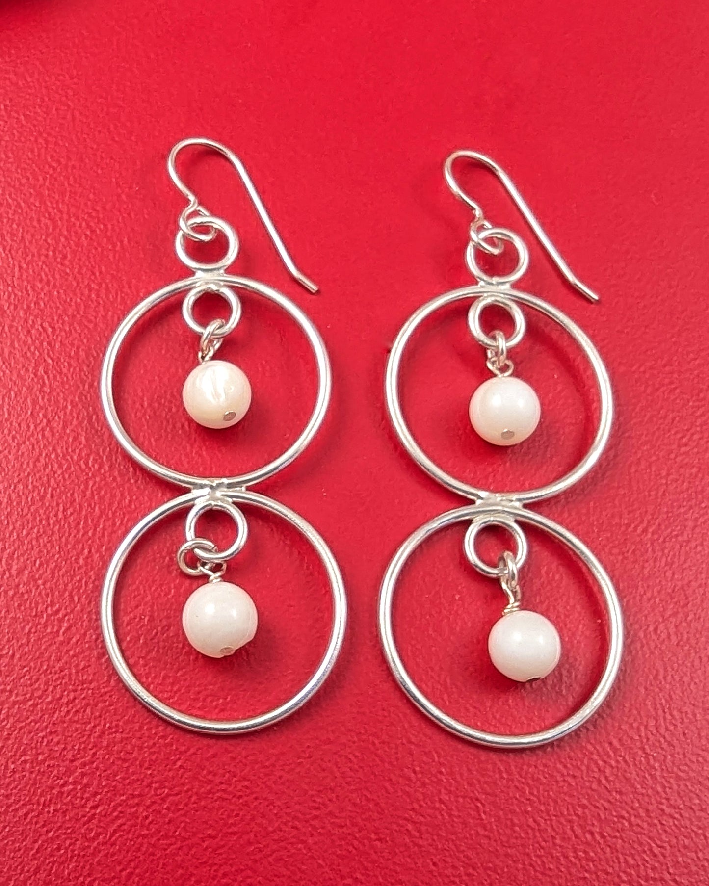 Sterling silver double dangle mother of pearl earrings on a red background