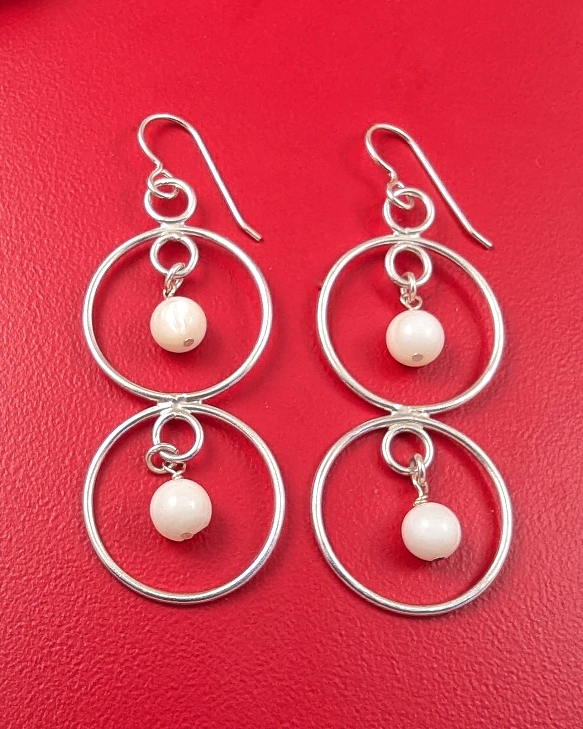 Sterling silver double dangle mother of pearl earrings on a red background