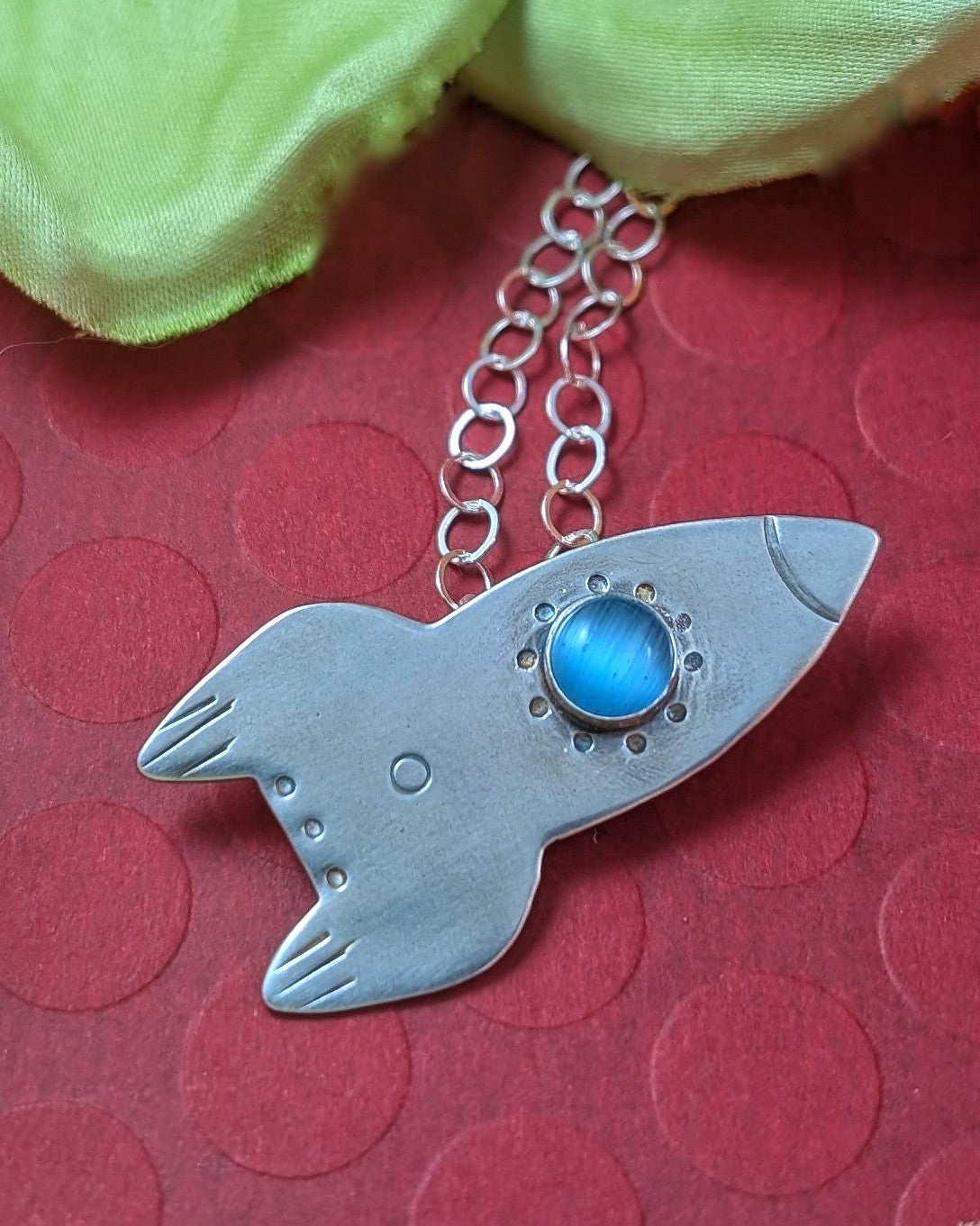 Sterling silver rocket ship necklace on a red background