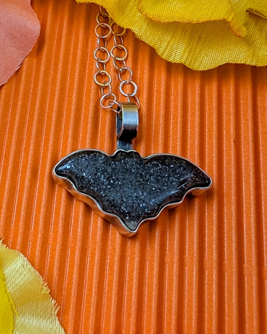 Bat necklace on an orange background