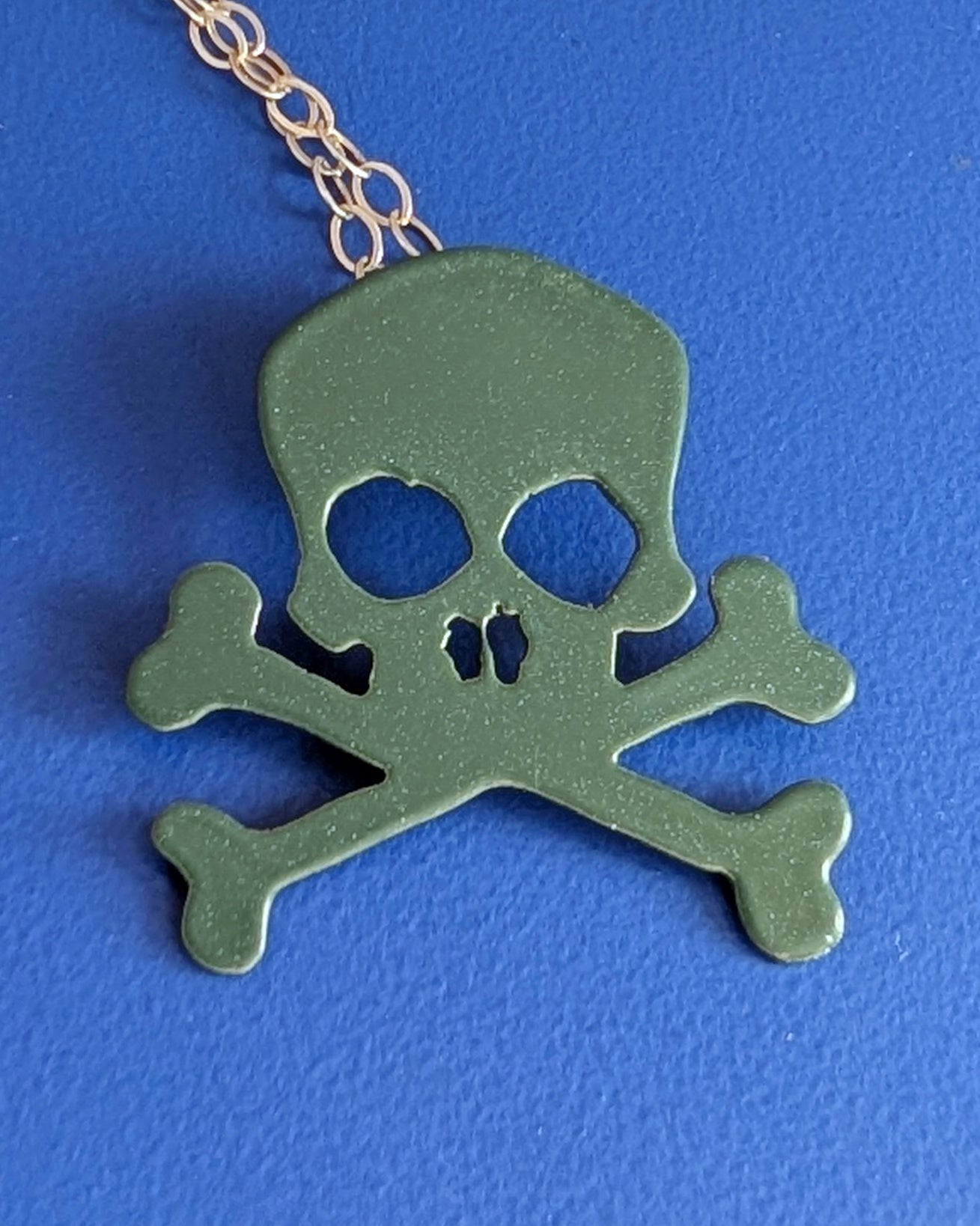 Military Green skull and crossbones pendant on a blue background