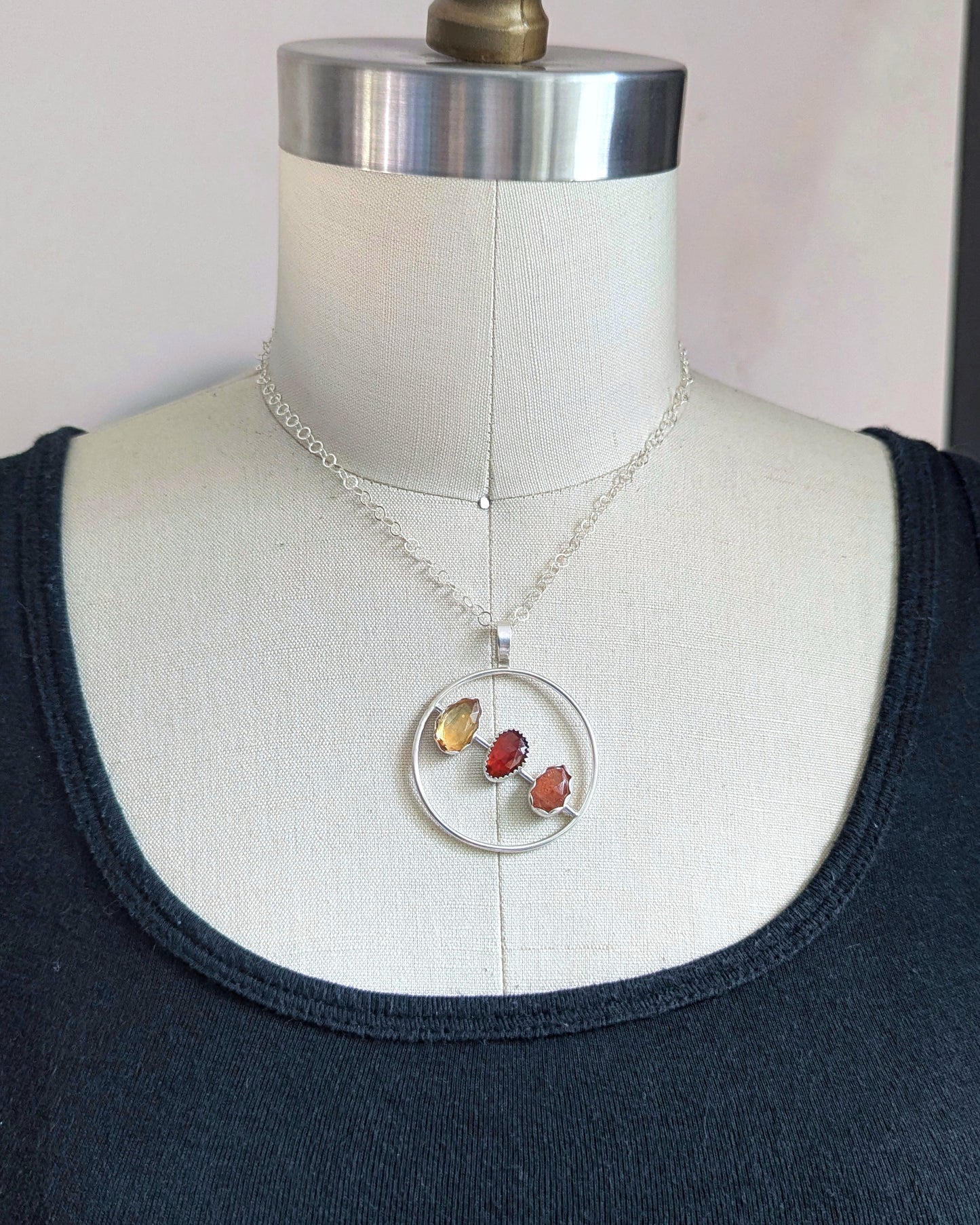 Mid mod inspired sterling silver circle with rosecut citrine, sunstone, and sunstone handmade to reflect its minimalism shown on a dress form