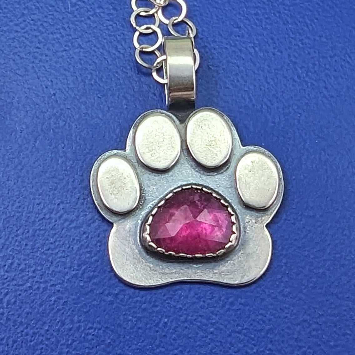 Rosecut ruby in a sterling silver paw necklace