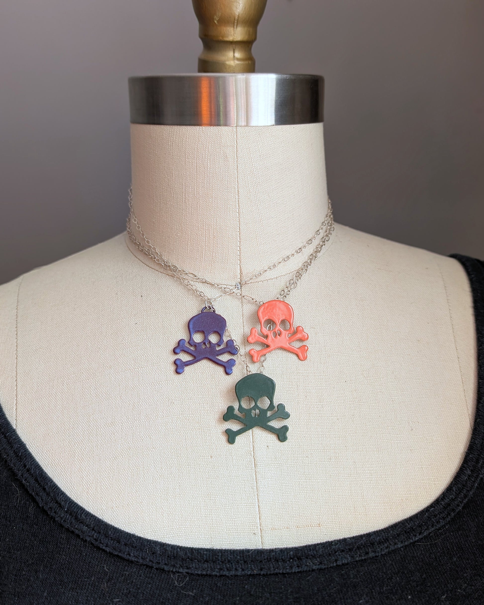 Three powdercoated colorful skull necklaces on a mannequin