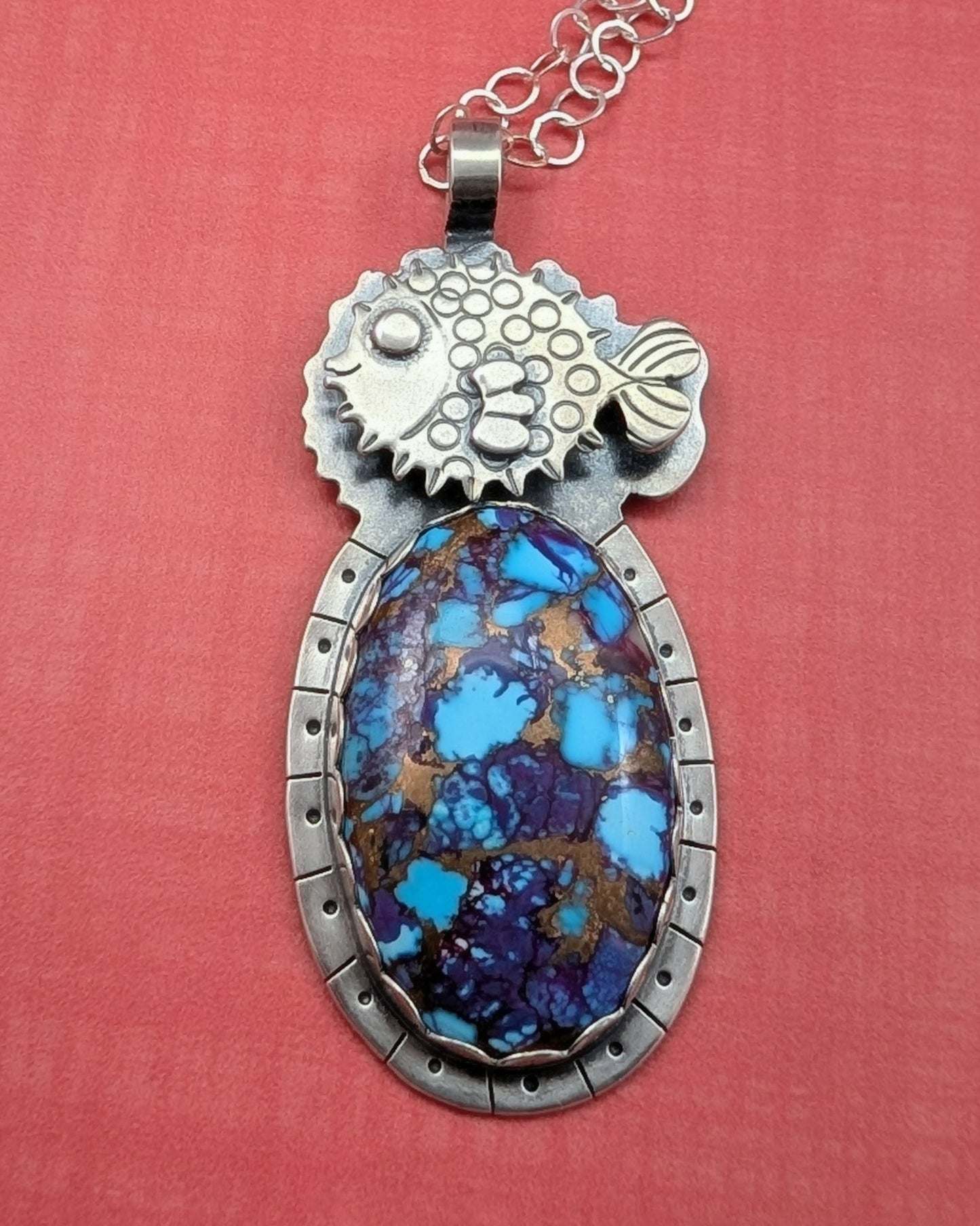 Puffer fish necklace with purple copper turquoise stone on orange background