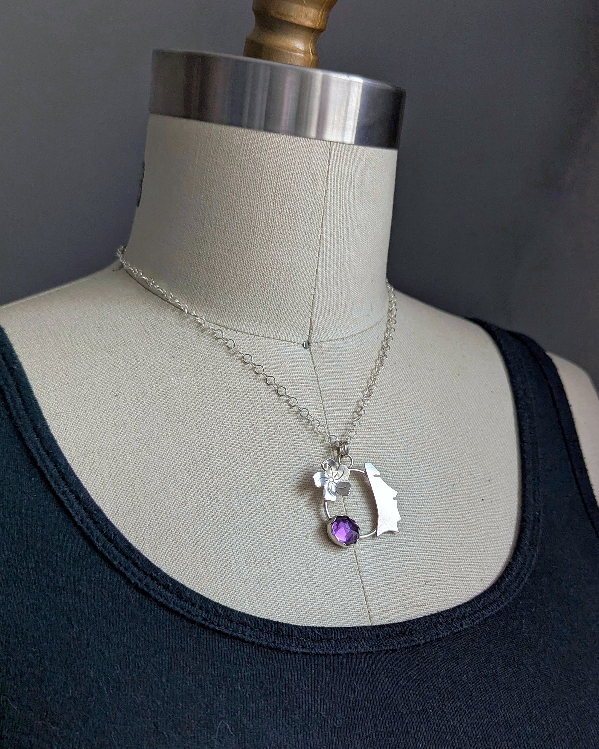Sterling silver and amethyst moai necklace on a dress form side view.
