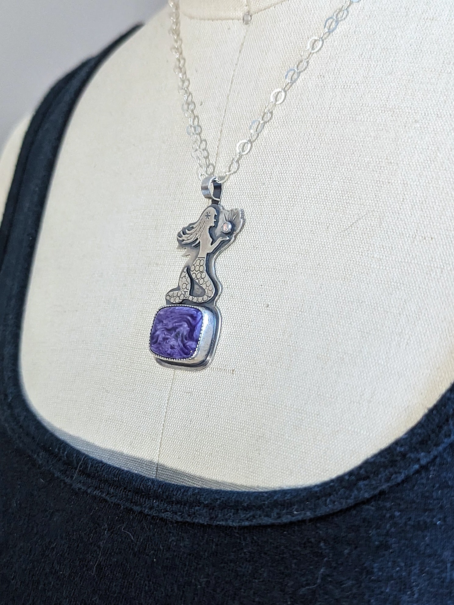 Charoite necklace with mermaid sitting on it 