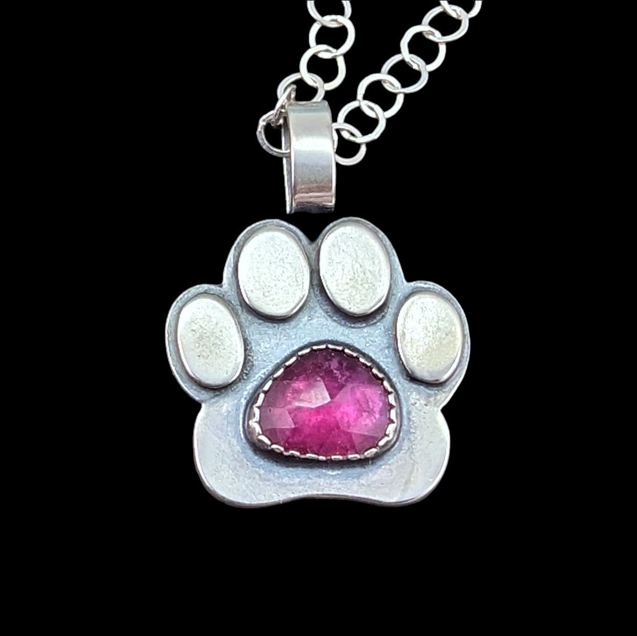 Paw print necklace in sterling silver and rosecut ruby in the center