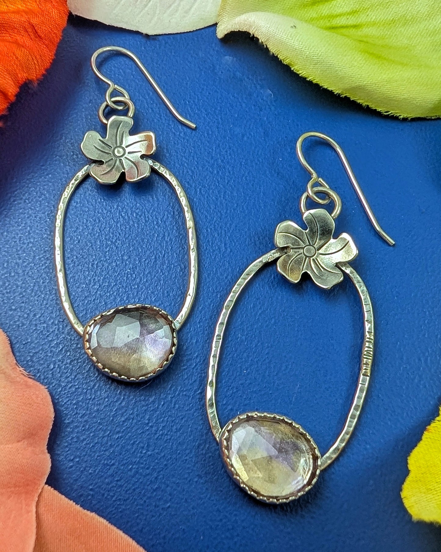 Sterling silver flower hoop earrings with ametrine on a blue background