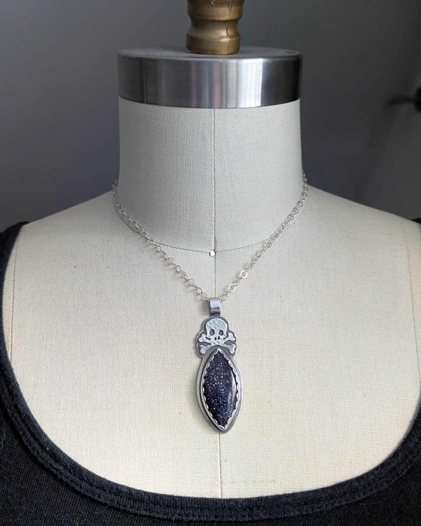 Sterling silver skull necklace with blue goldstone on a mannequin
