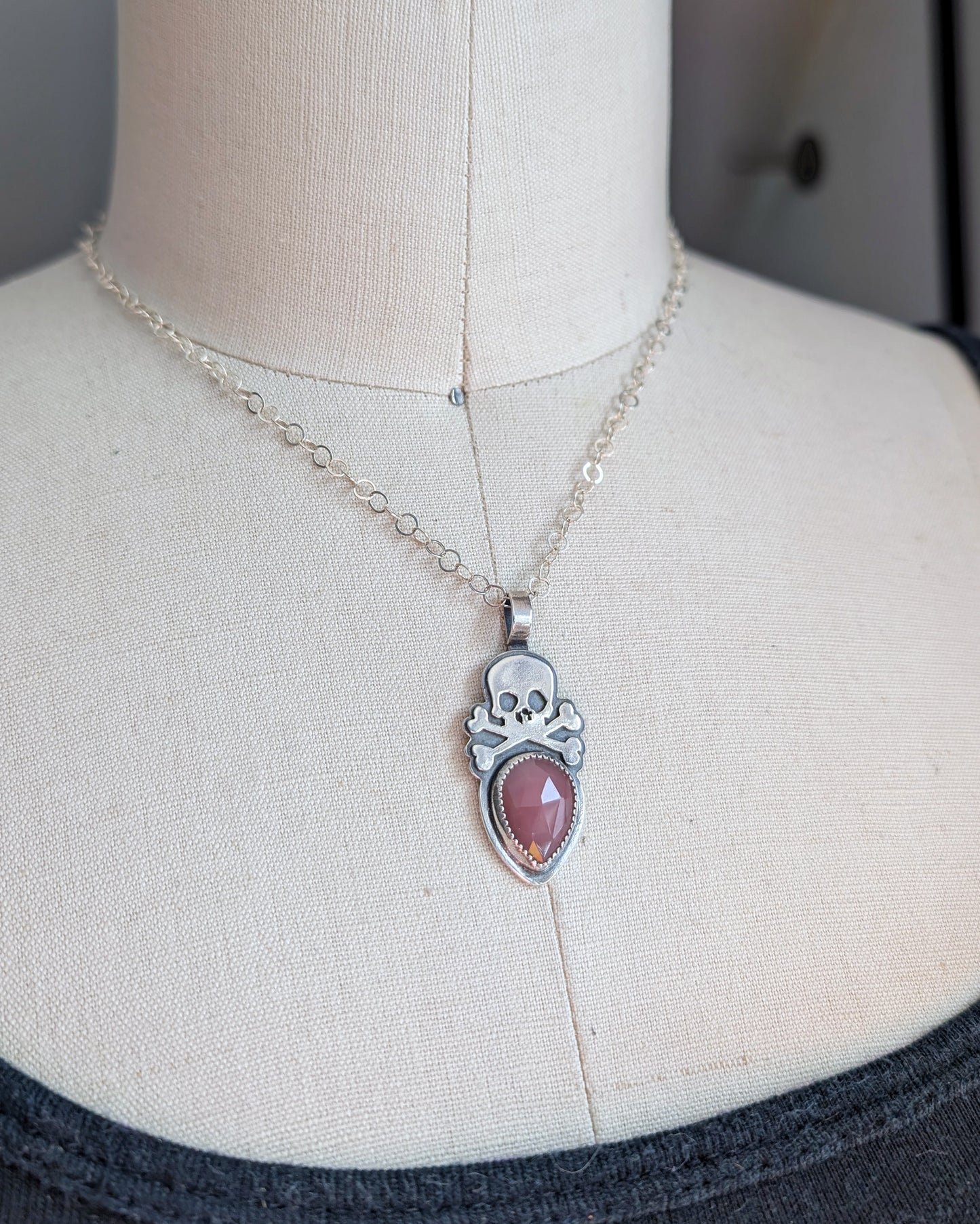 Sterling silver skull with rosecut guava quartz necklace on mannequin at an angle
