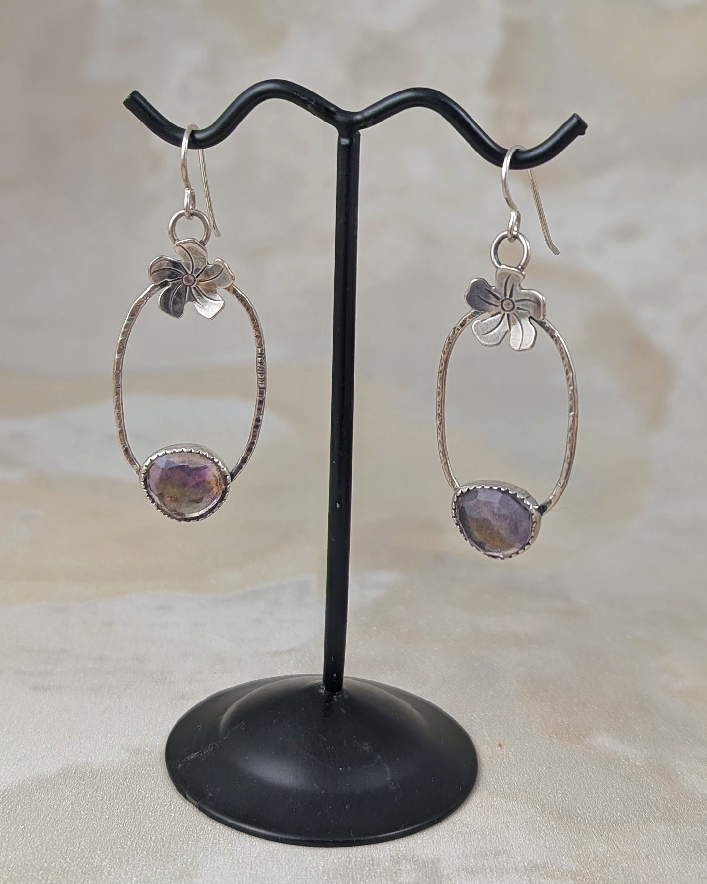 Sterling silver flower hoop earrings with ametrine on an earring stand