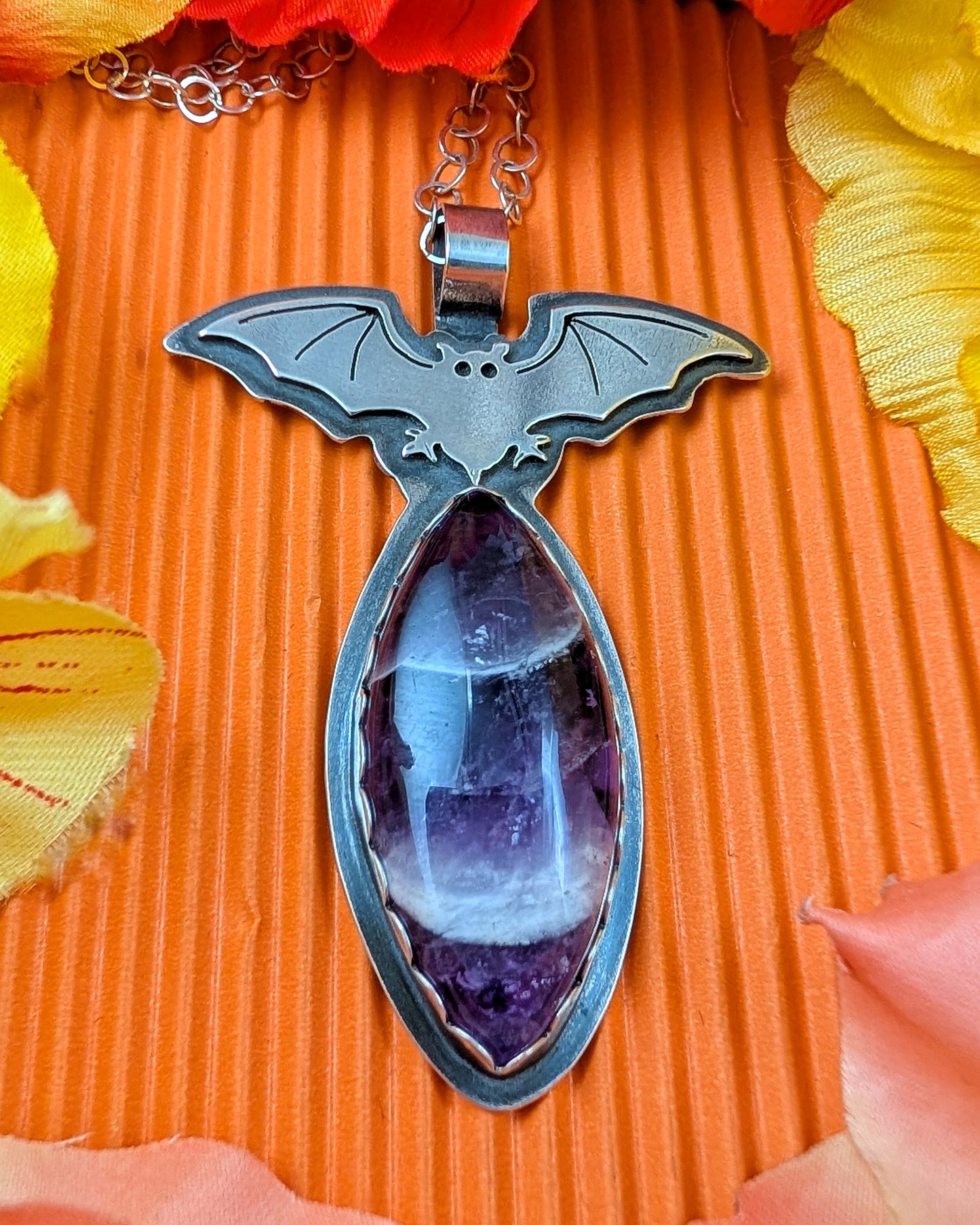 Sterling silver bat necklace with chevron amethyst on orange background with flowers