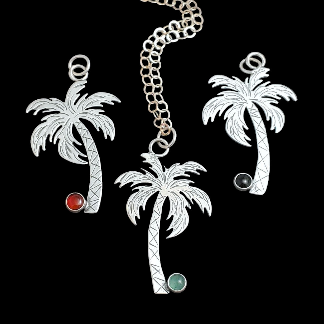 Handmade sterling silver palm tree necklaces with gemstone coconuts.
