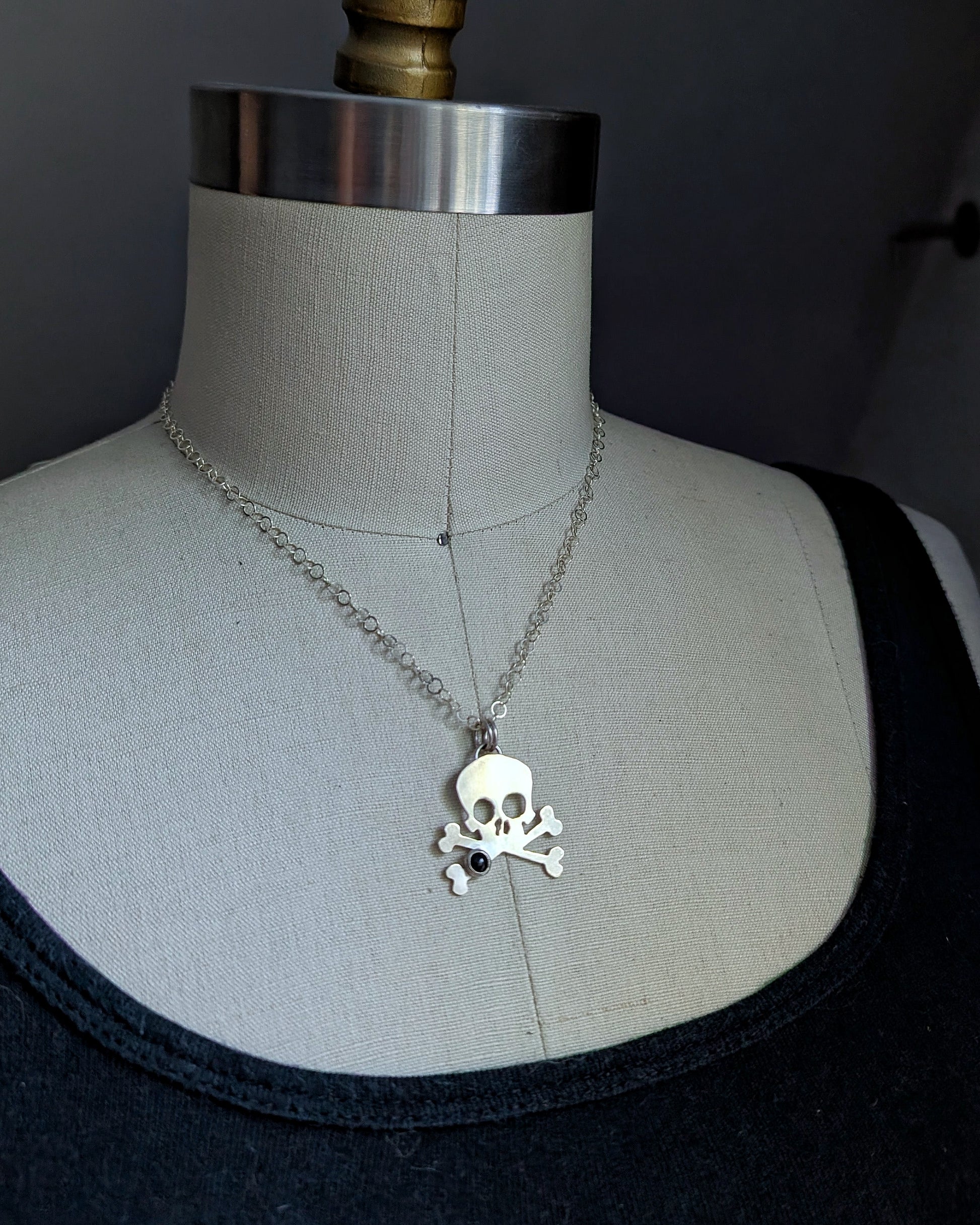 Silver skull necklace on a mannequin with a dark background