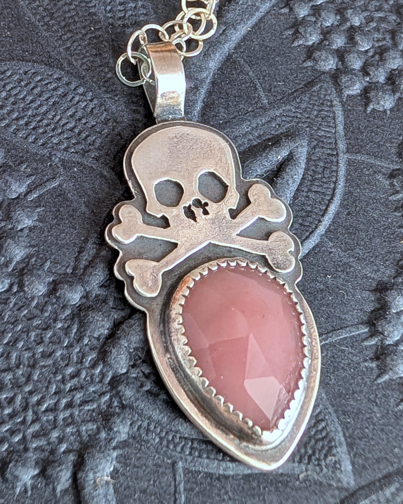 Sterling silver skull with rosecut guava quartz necklace on black floral background