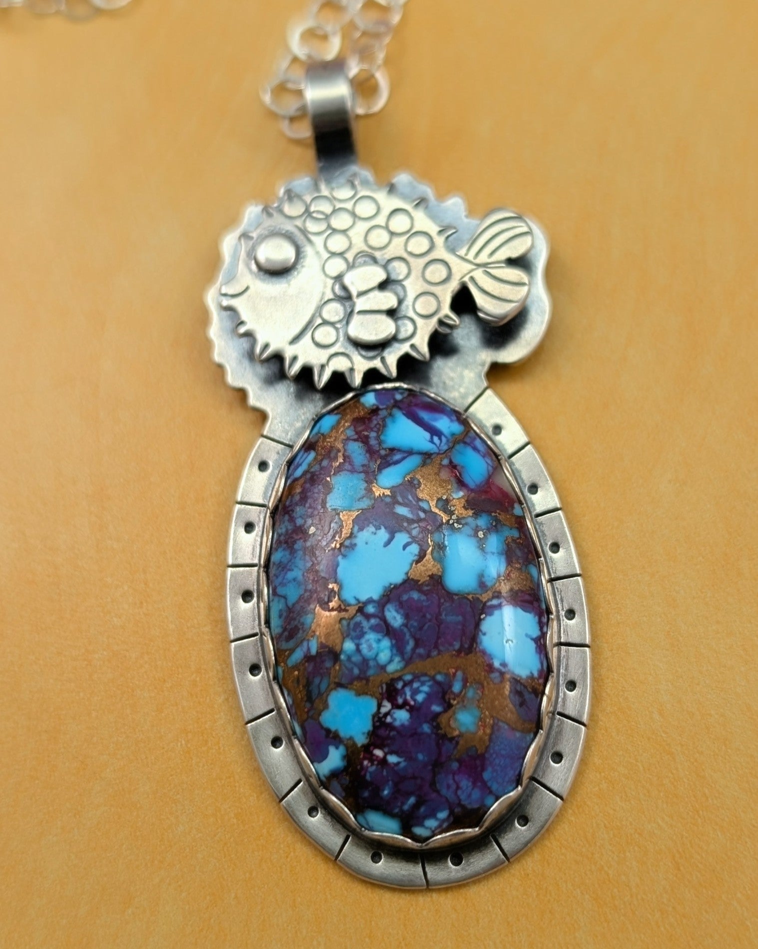 Puffer fish necklace with purple copper turquoise stone on yellow background