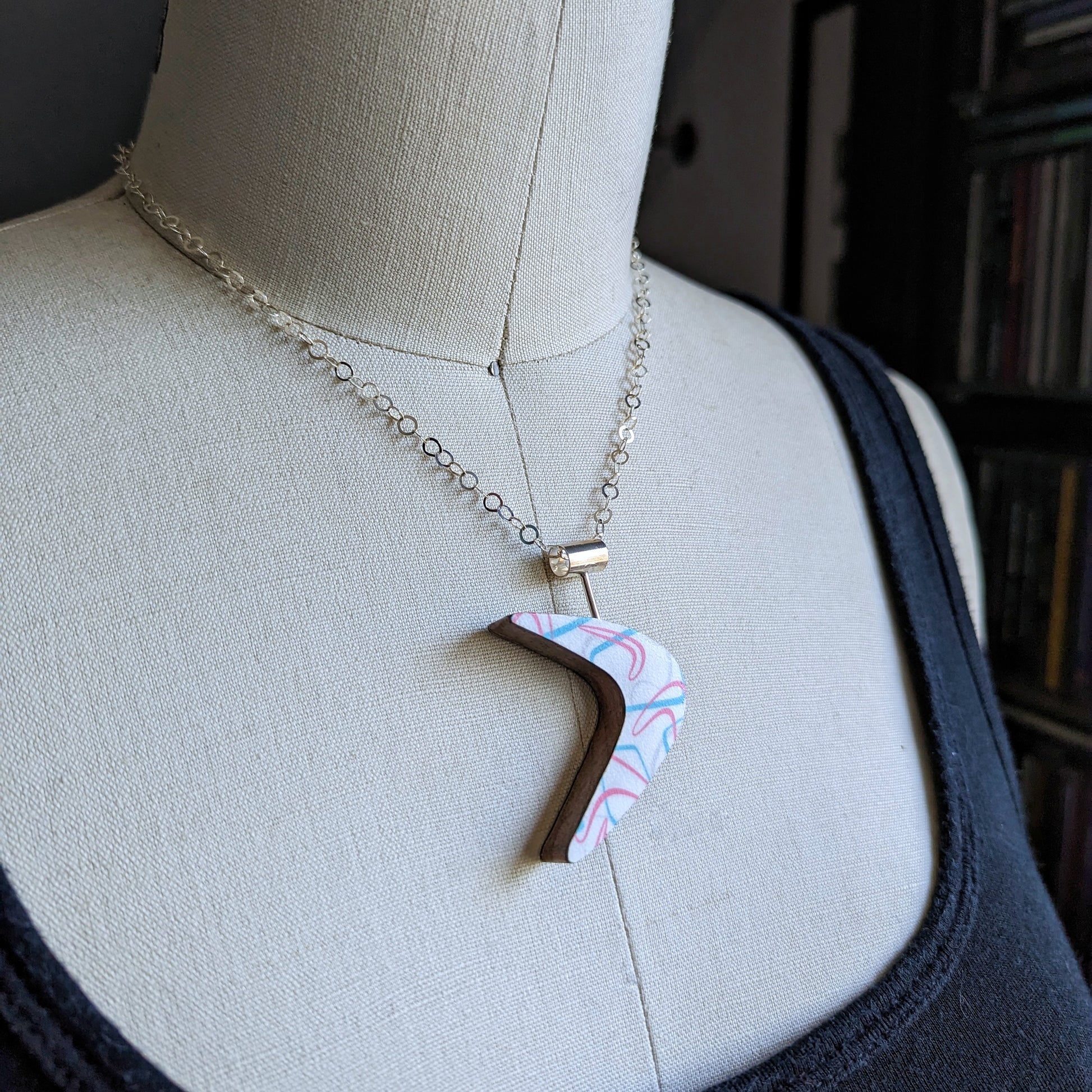 Boomerang shaped laminate on wood necklace on dress form to show size