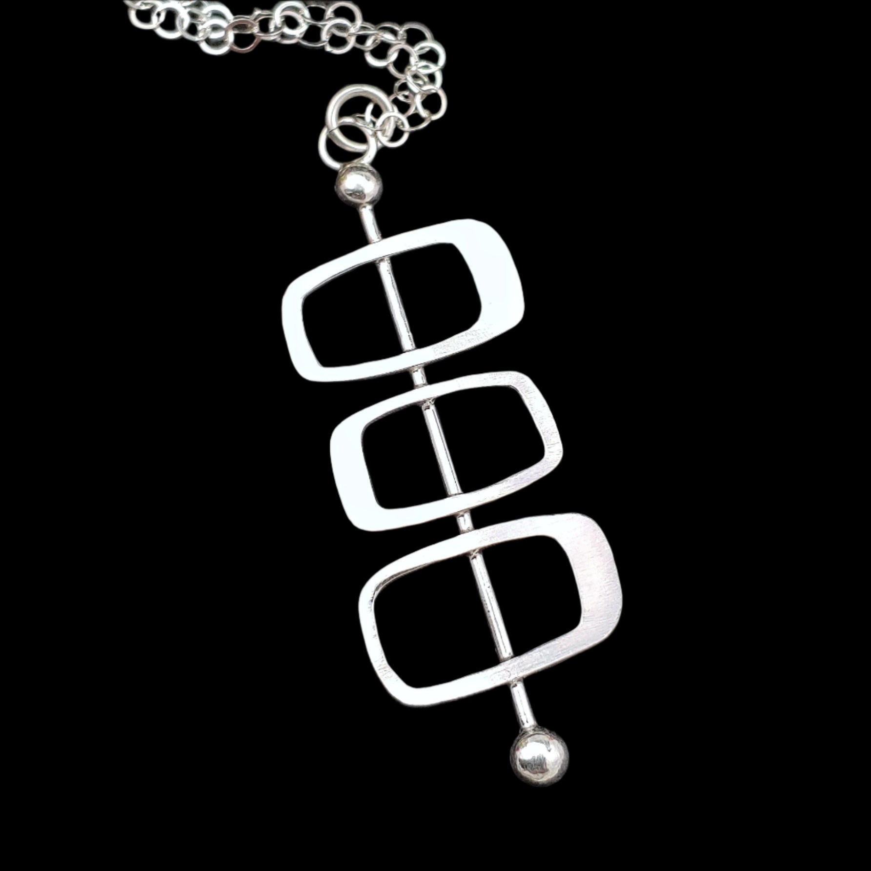 Handmade sterling silver modernist necklace featuring Googie inspired architectural soft rectangles on a plain back background