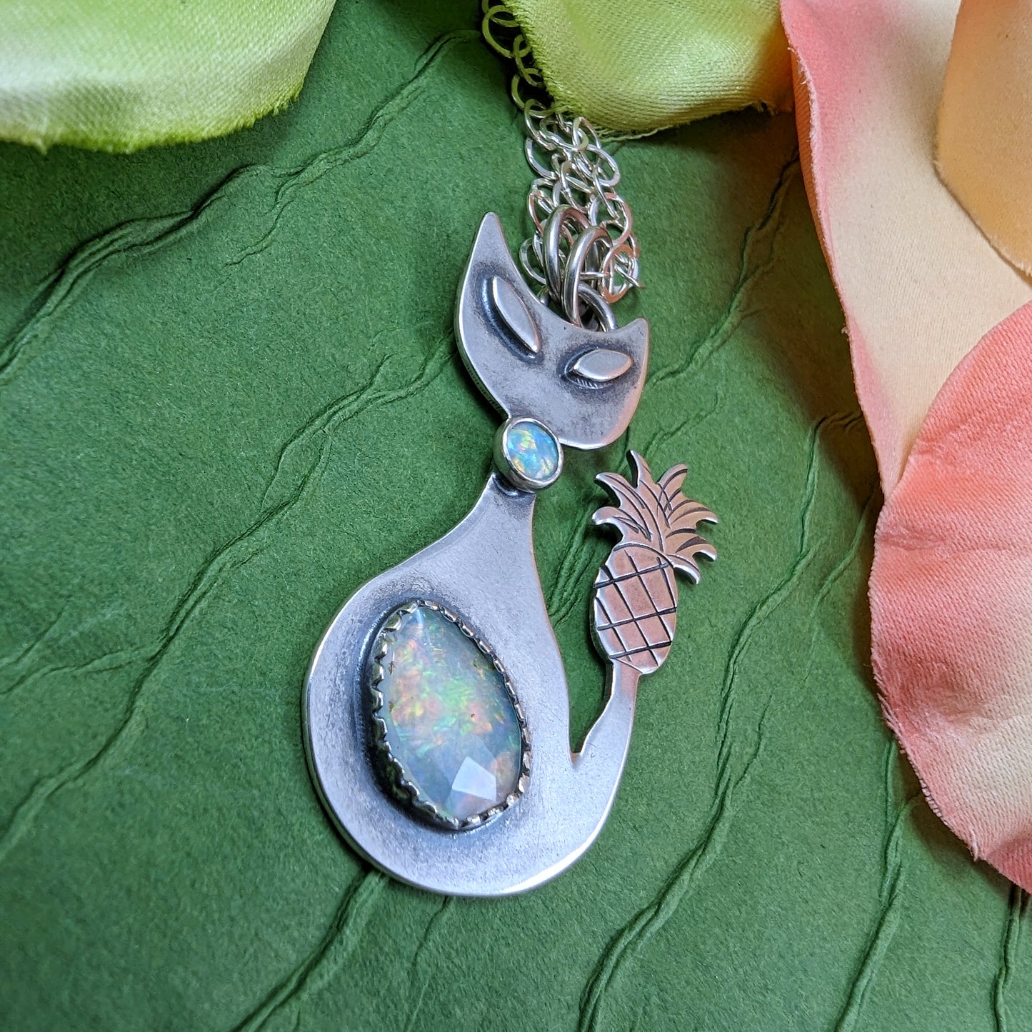 Sterling silver handmade cat with pineapple tail and Ethiopian opal on a green background