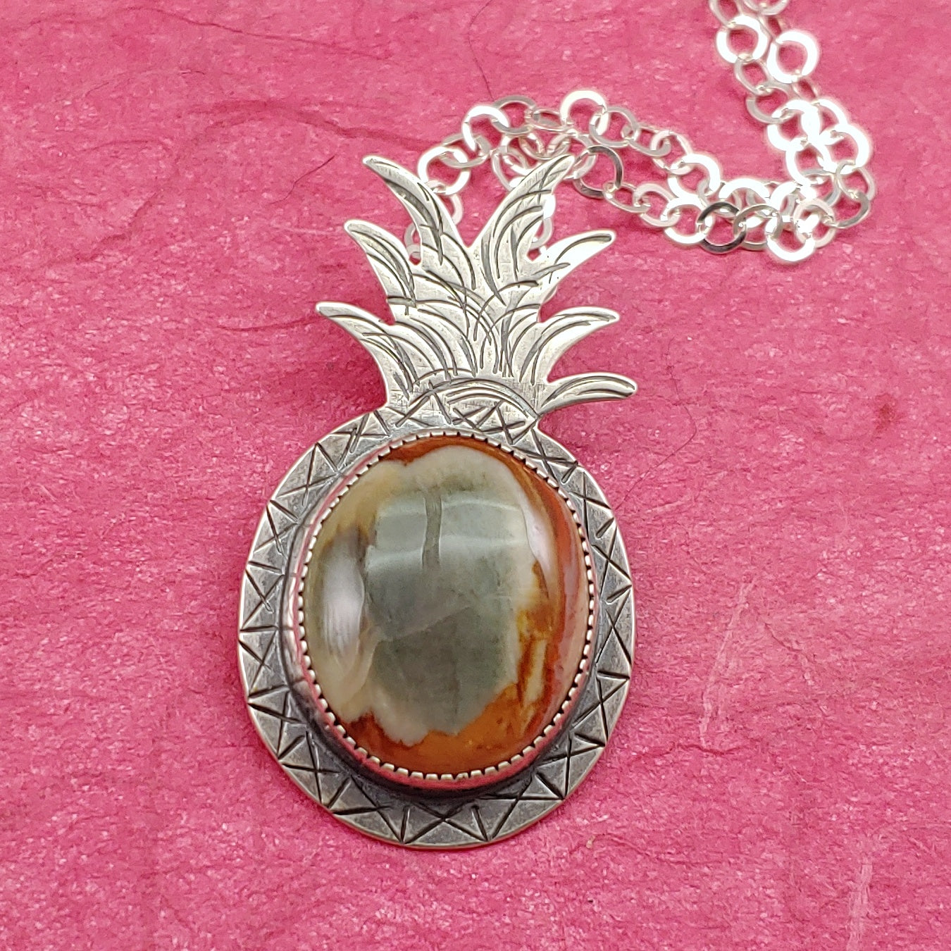 Handmade sterling silver pineapple with a mookaite jasper stone in the center.