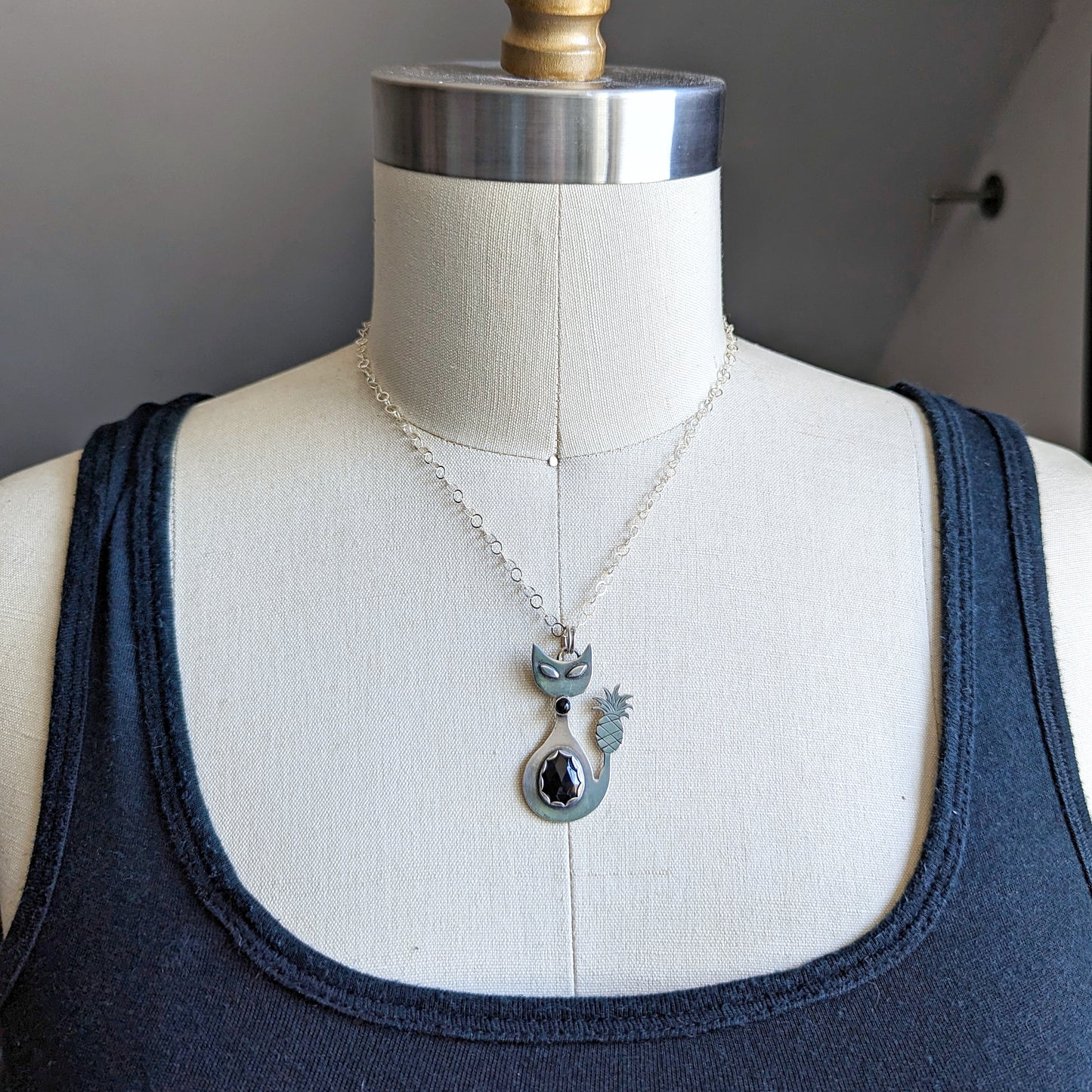 Sterling silver handmade cat with pineapple tail and rosecut onyx on a dress form