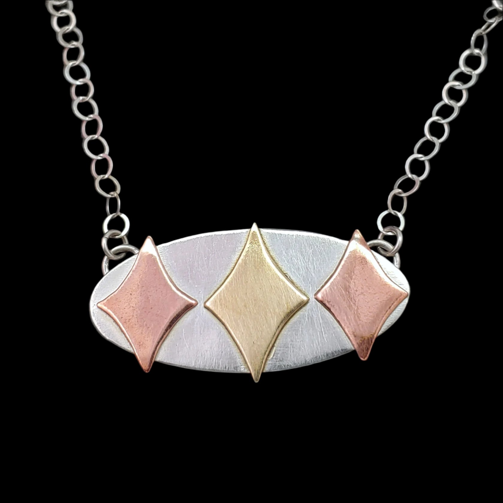 Mid century modern necklace handmade in sterling silver with copper and brass retro stars in an oval setting