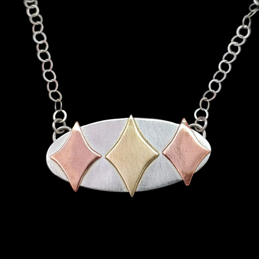 Mid century modern necklace handmade in sterling silver with copper and brass retro stars in an oval setting