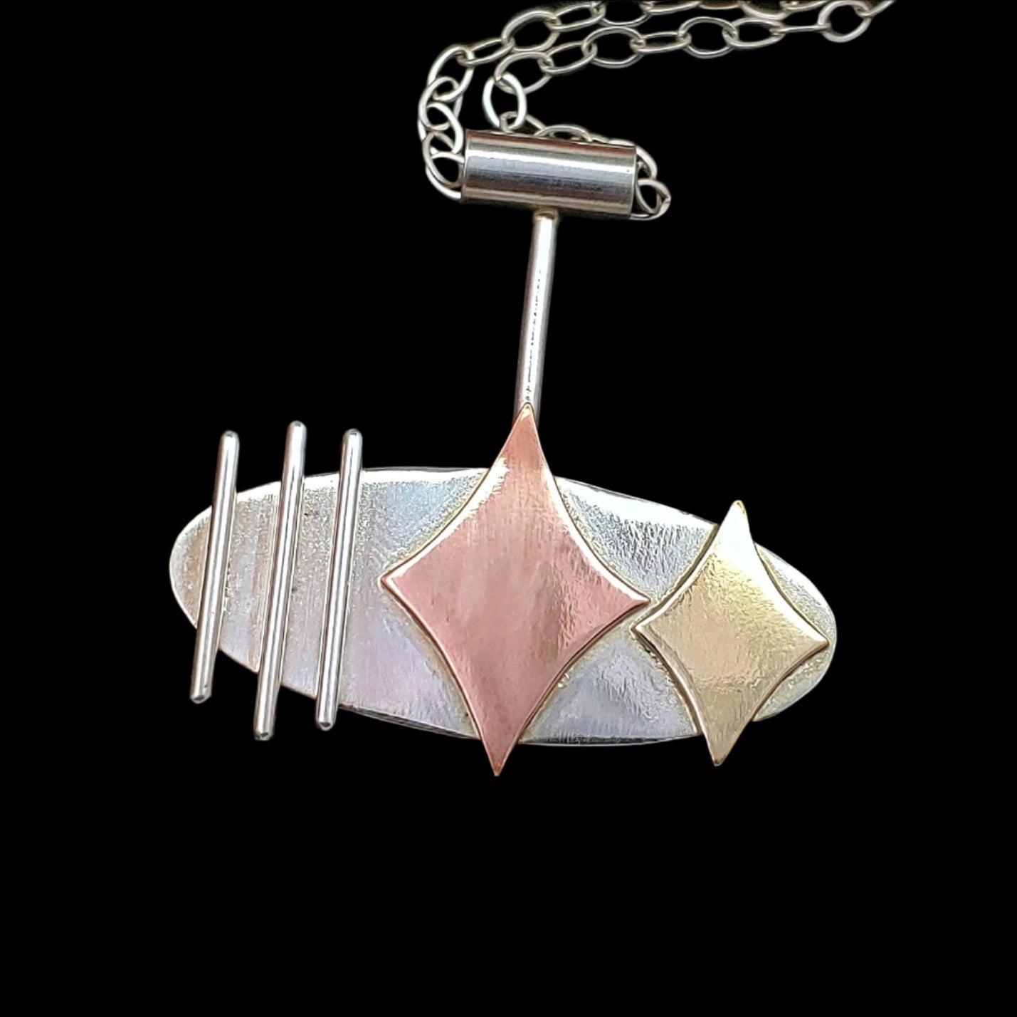 Mid century modern necklace handmade in sterling silver with copper and brass retro stars, and silver bars in an oval setting