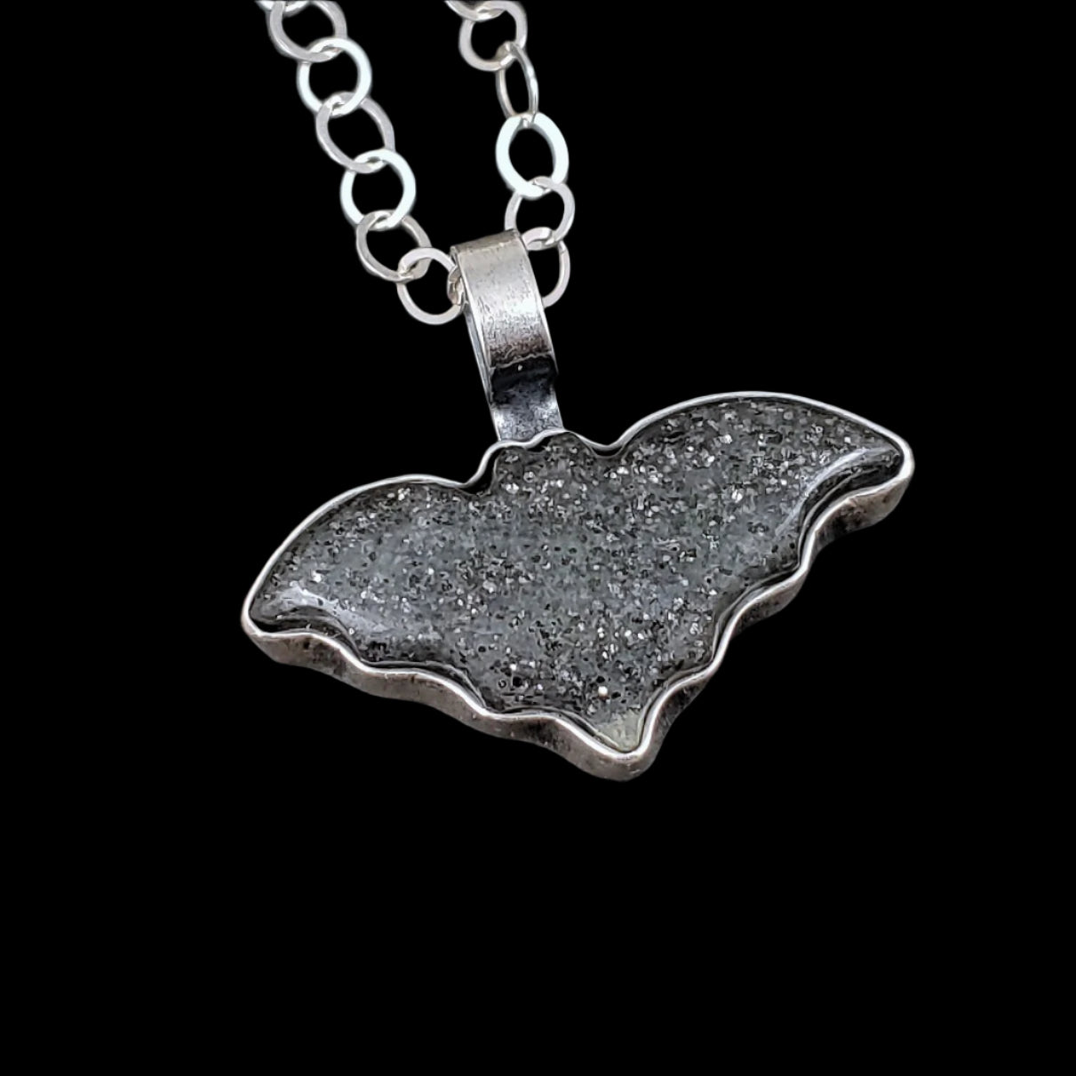 Midnight quartzite bat necklace on a black background.