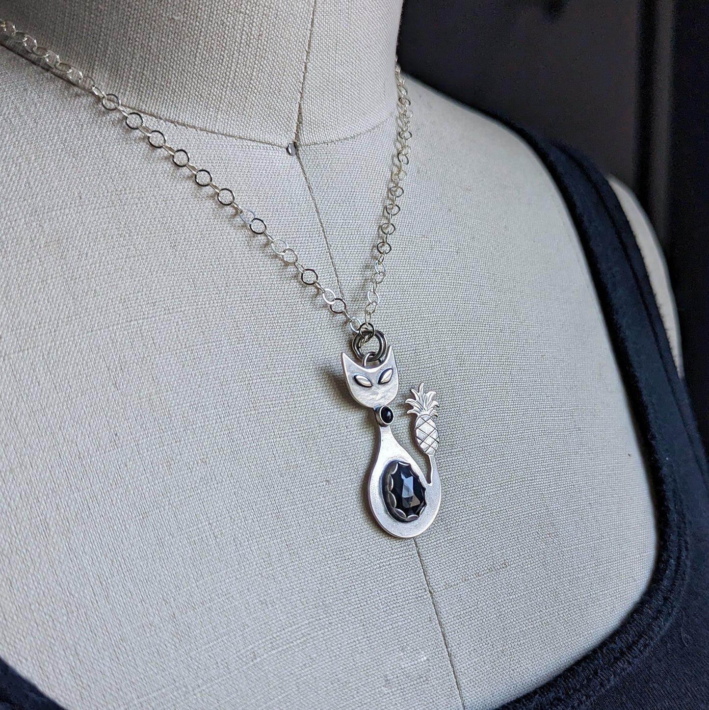 Sterling silver handmade cat with pineapple tail and rosecut onyx on a dress form with a side view