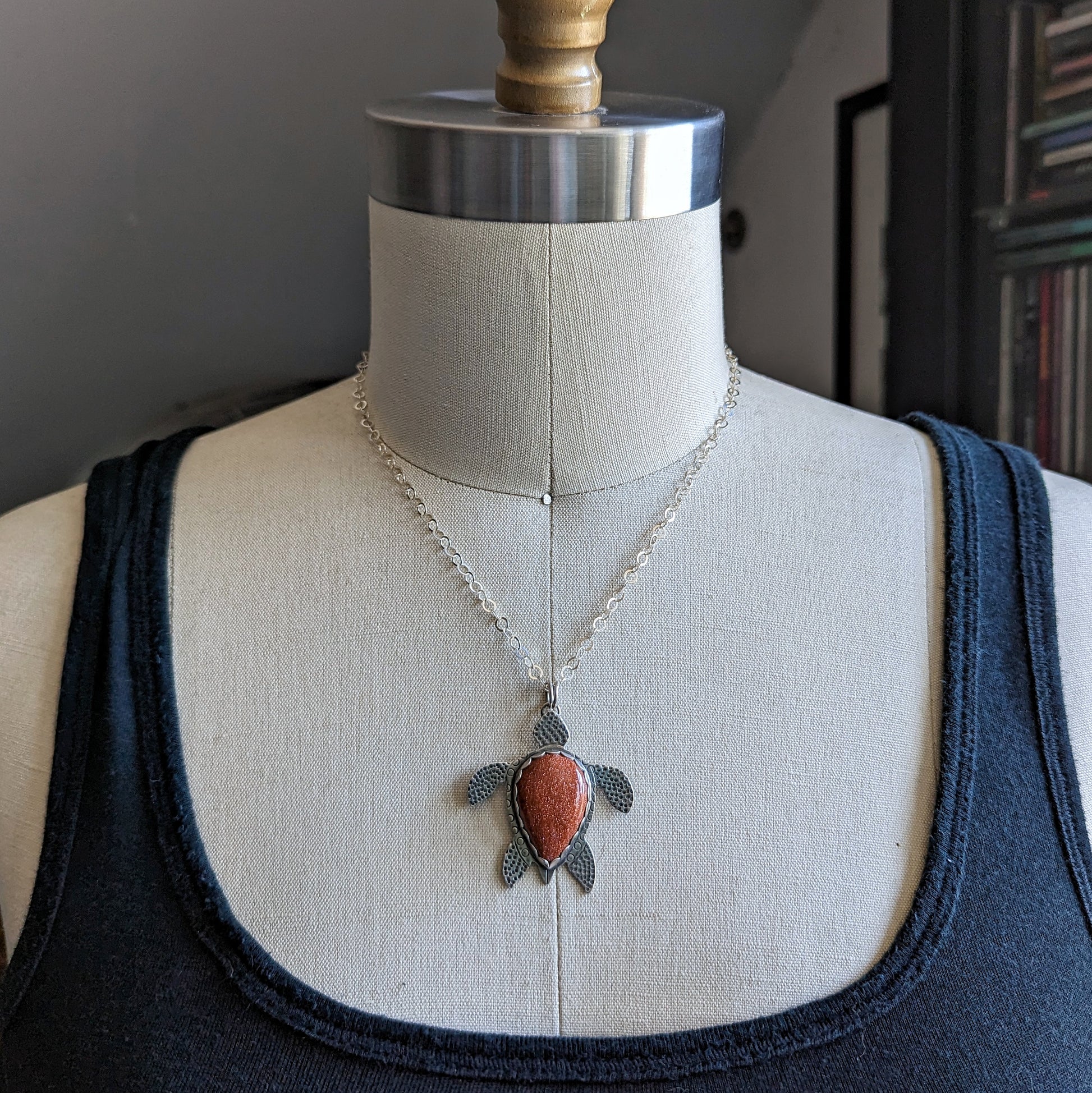 Sterling silver handmade sea turtle necklace with goldstone on dress form