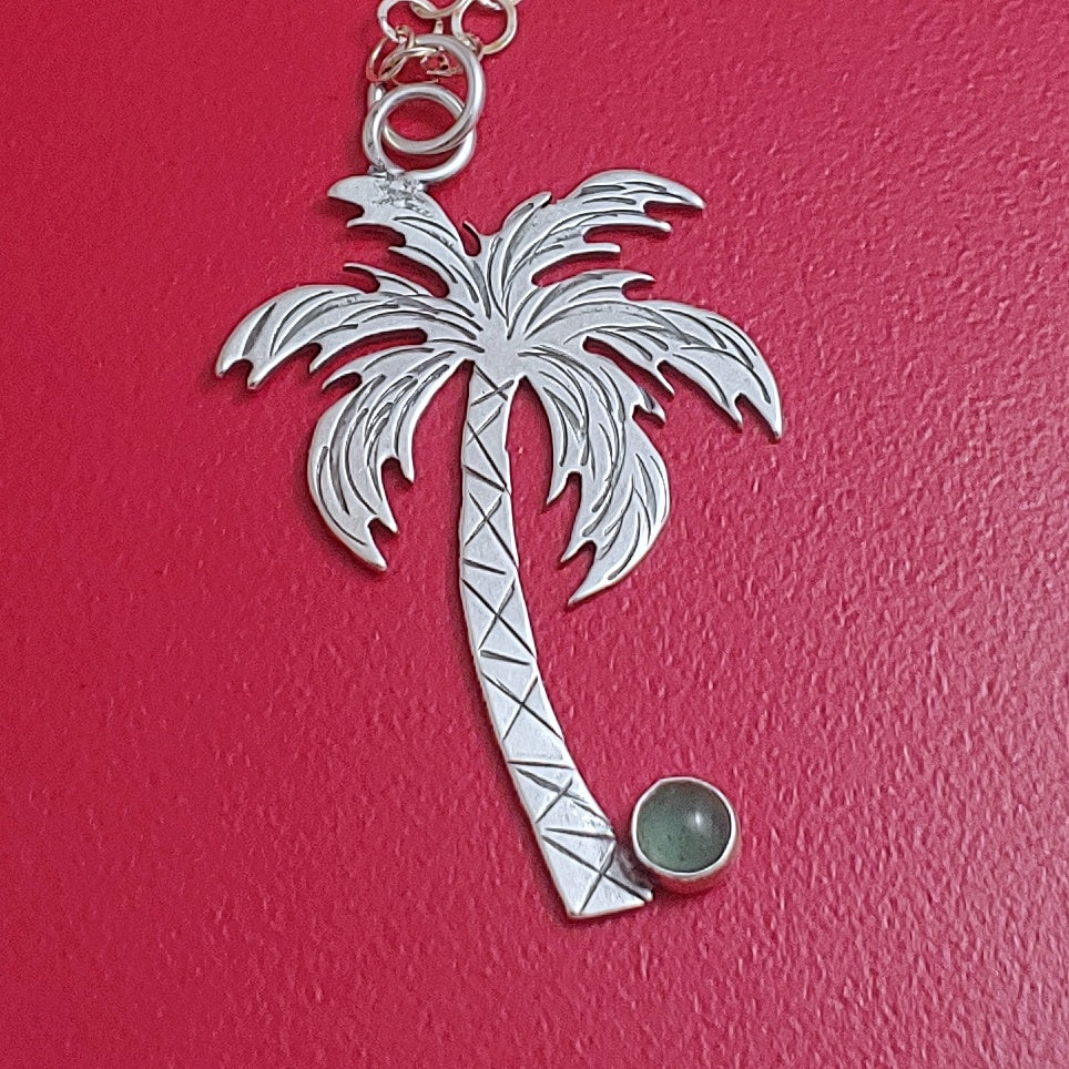 Sterling silver palm tree Tiki necklace with a green stone as the coconut.