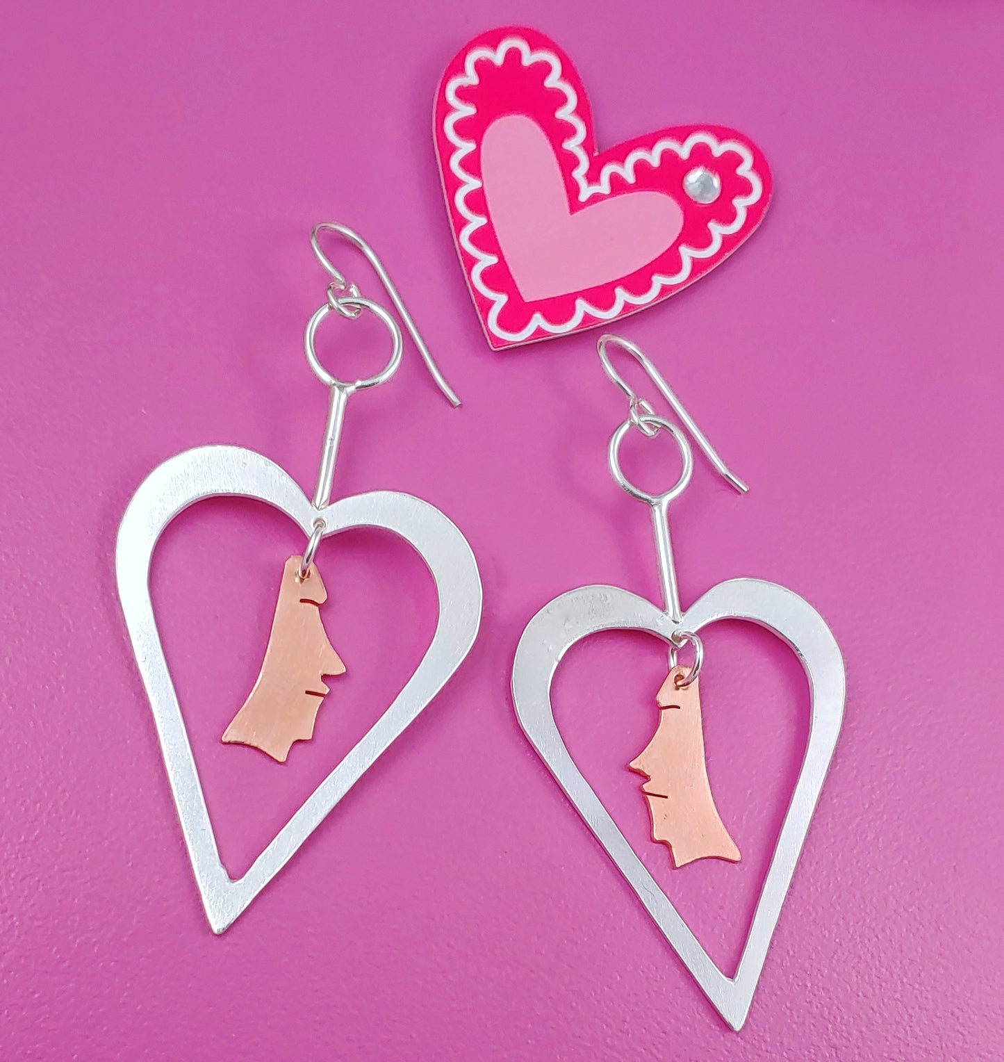 Sterling silver heart shaped earrings with copper necklace dangling from the centers