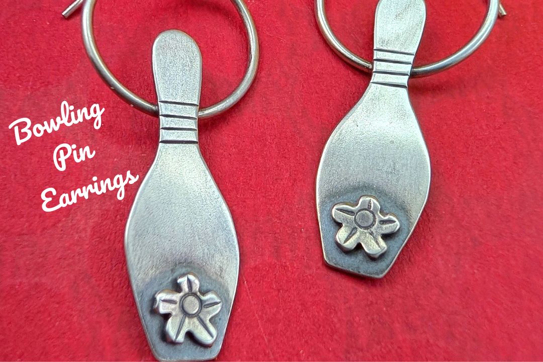 Sterling silver bowling pin earrings on a red background