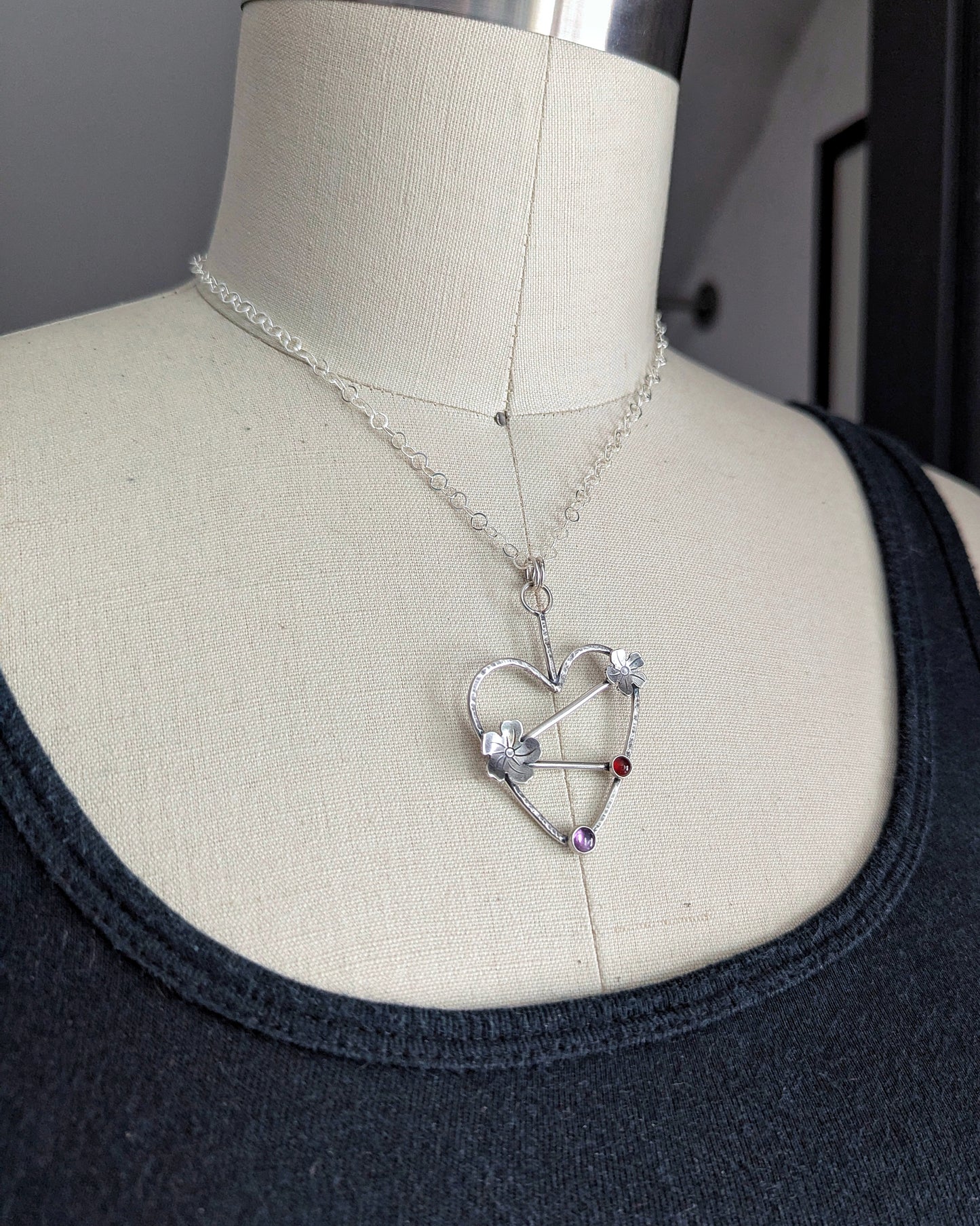 Sterling silver handmade heart necklace with Tiki plumeria flower details and carnelian and pink stones on a dress form