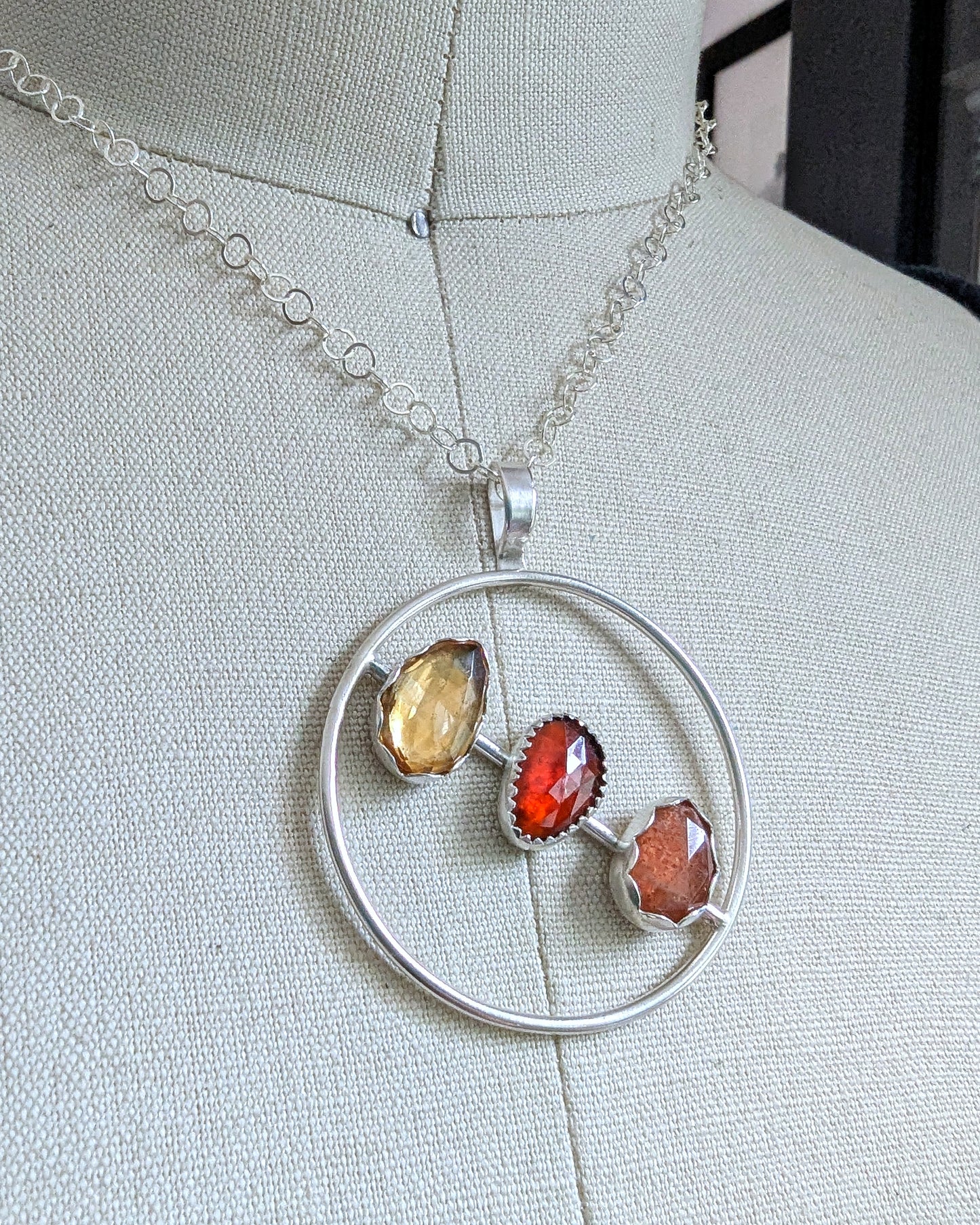 Sterling silver necklace with rosecut citrine, garnet, and sunstone shown on a dress form