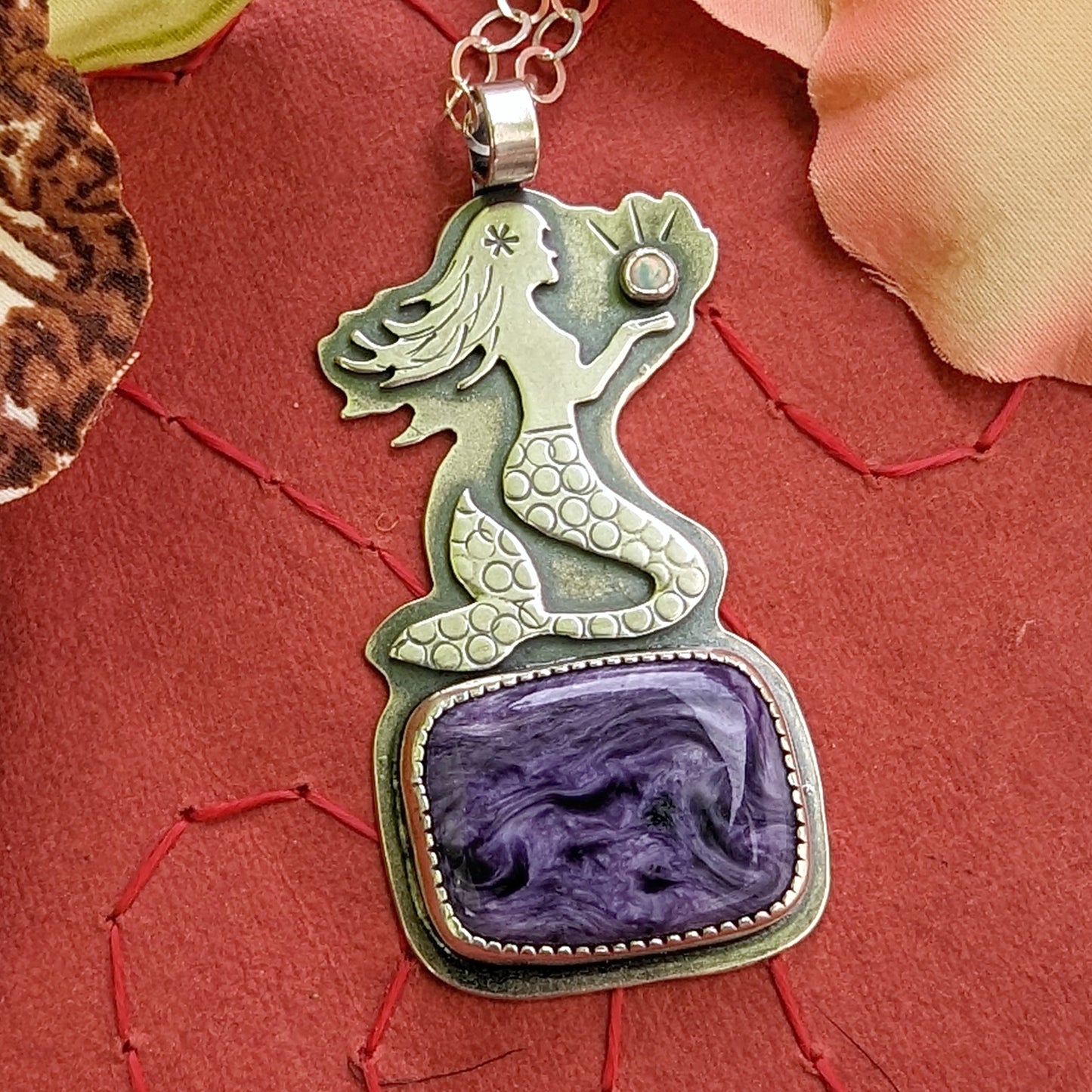 Sterling silver mermaid on charoite on red background