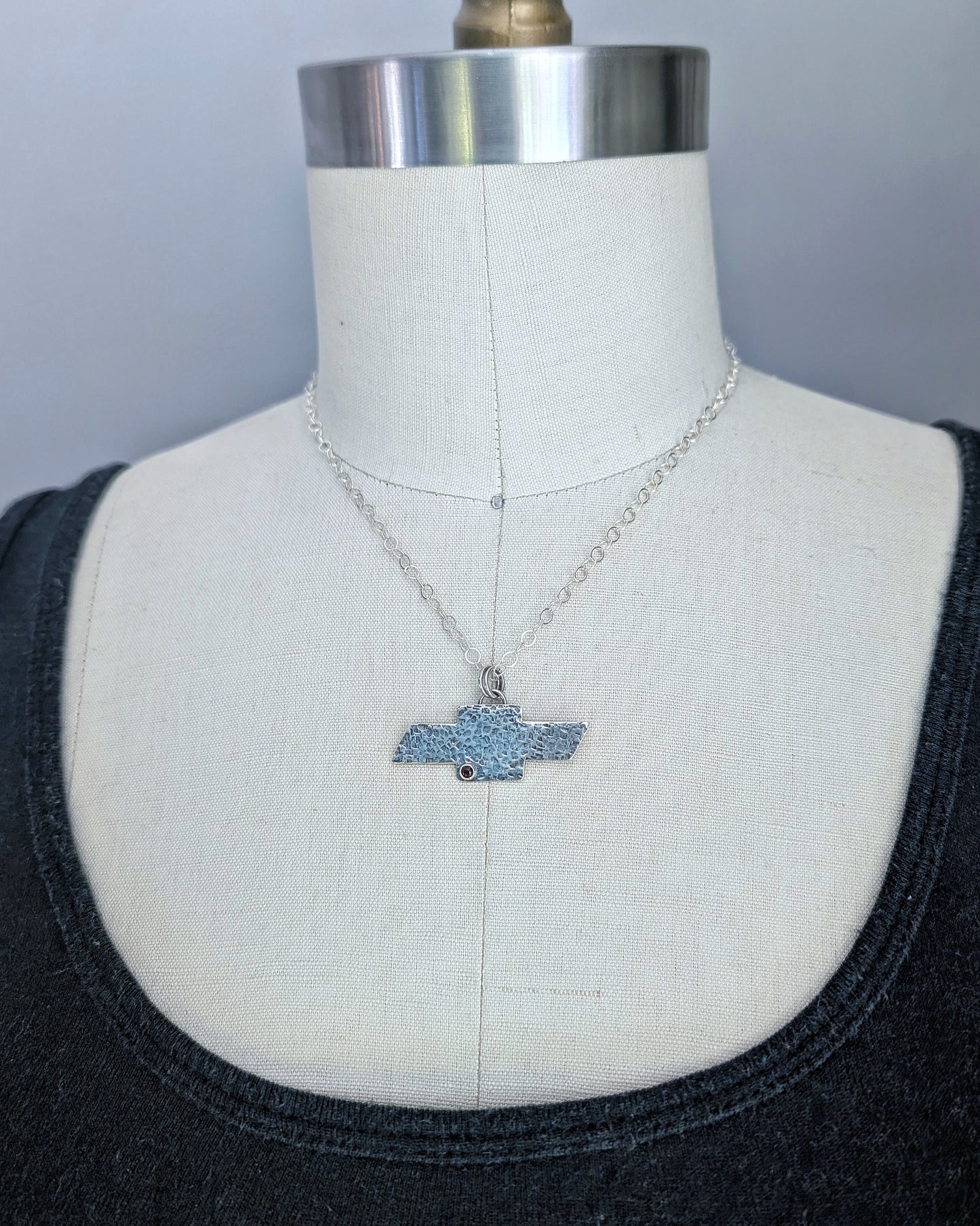 Sterling silver Chevrolet bowtie necklace on a mannequin.