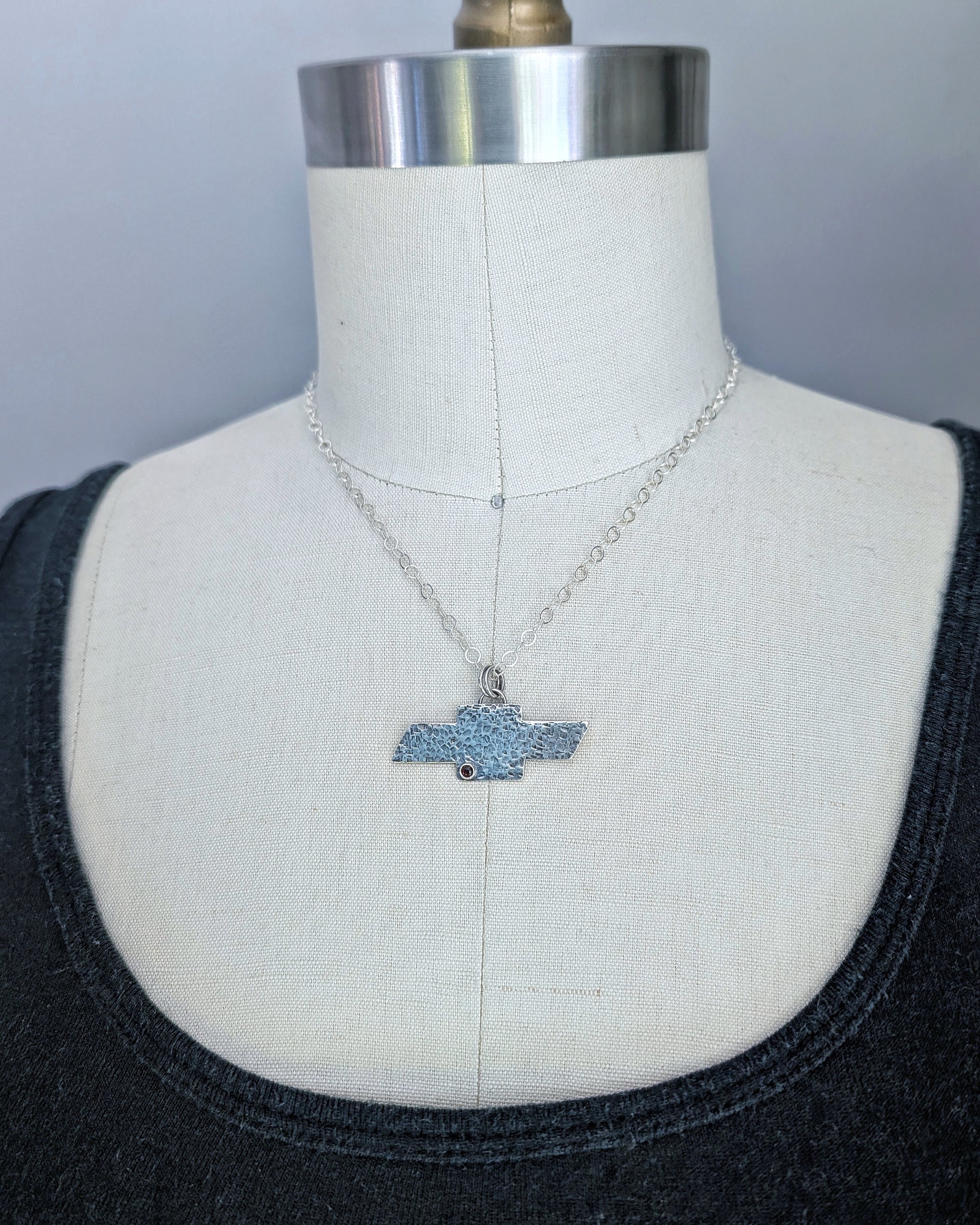 Sterling silver Chevrolet bowtie necklace on a mannequin.