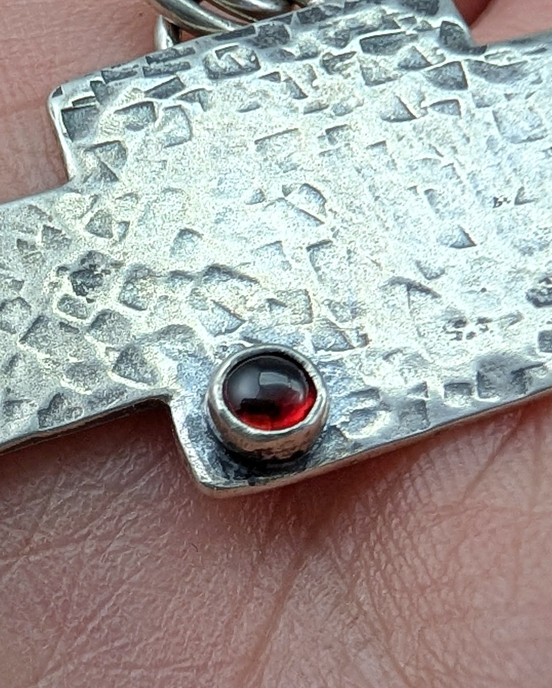 Close up of garnet on the chevy bowtie logo necklace