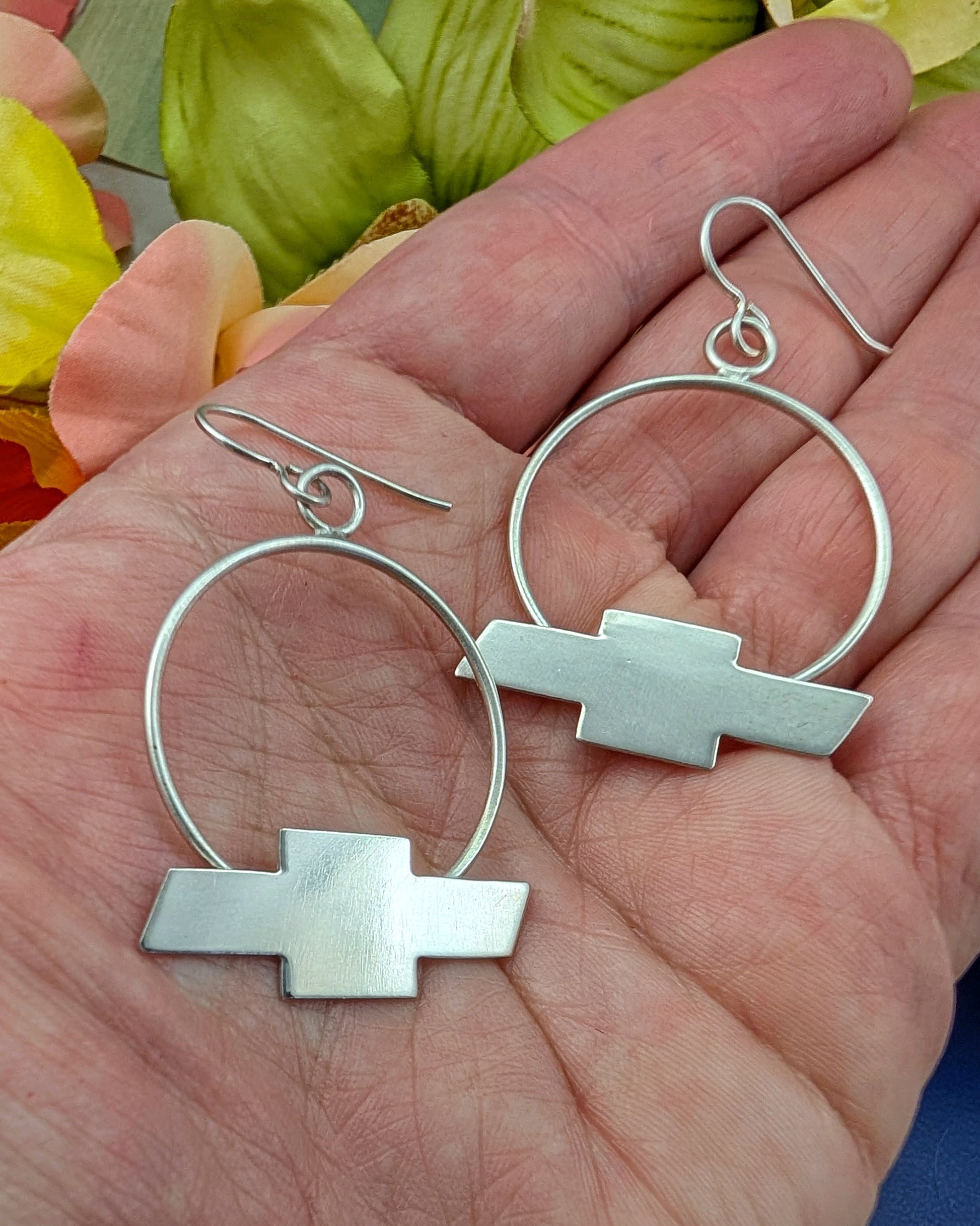 Sterling silver Chevrolet bow tie earrings on my hand