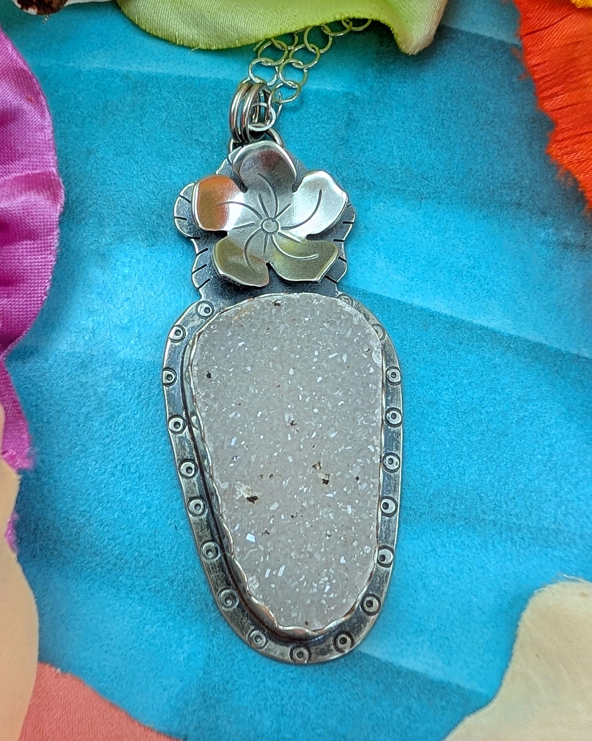White druzy and flower necklace on a turquoise colored background